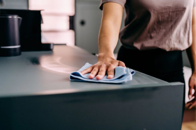 A hand wiping a counter with a blue cloth.