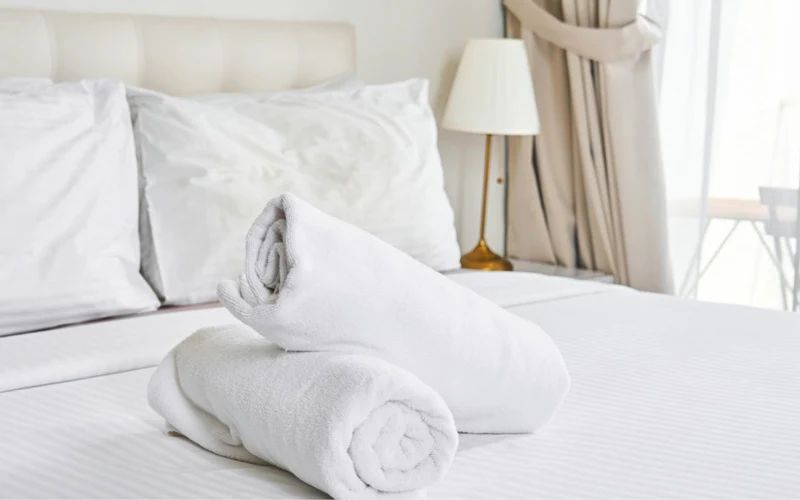 a bed with white sheets , pillows , and towels on it .