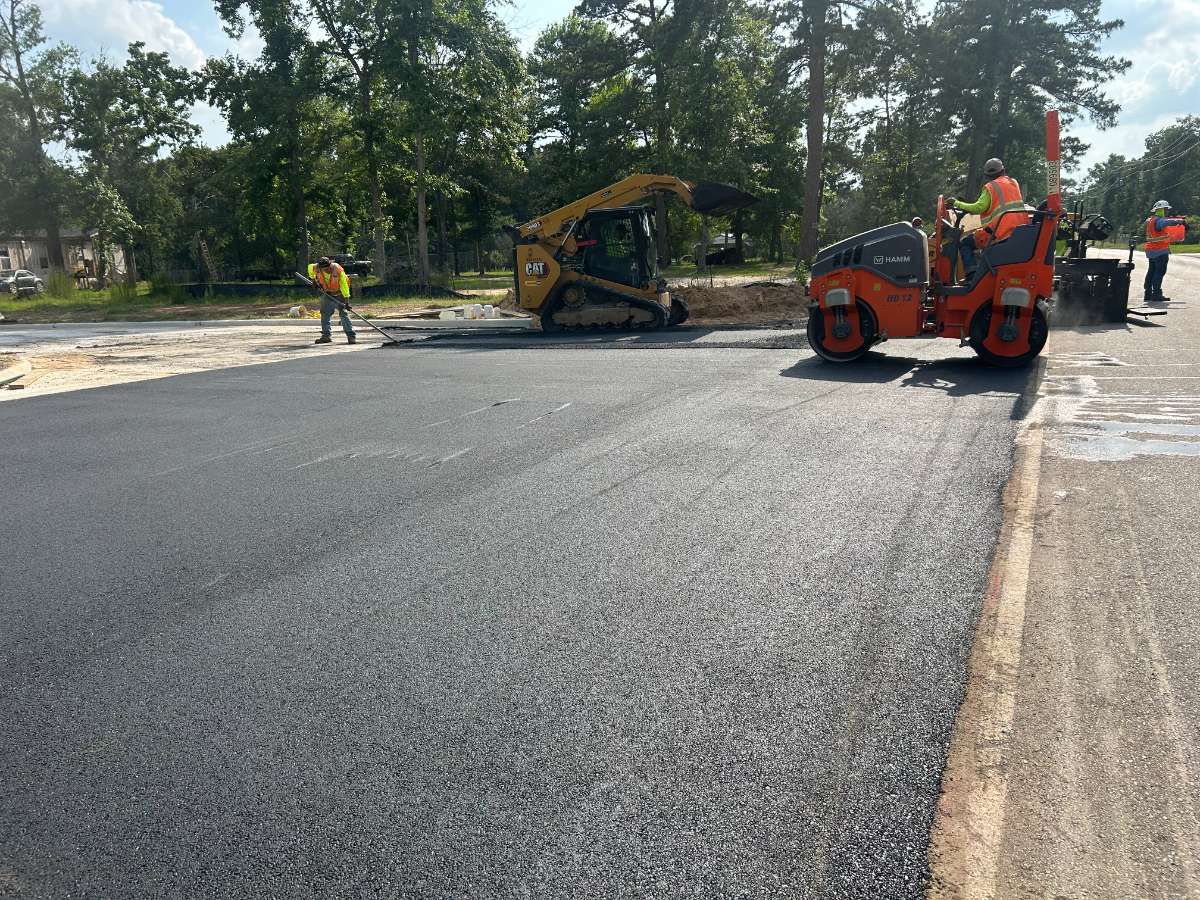 Freshly paved residential community street with AAA Paving crew finishing edges in the Houston metro