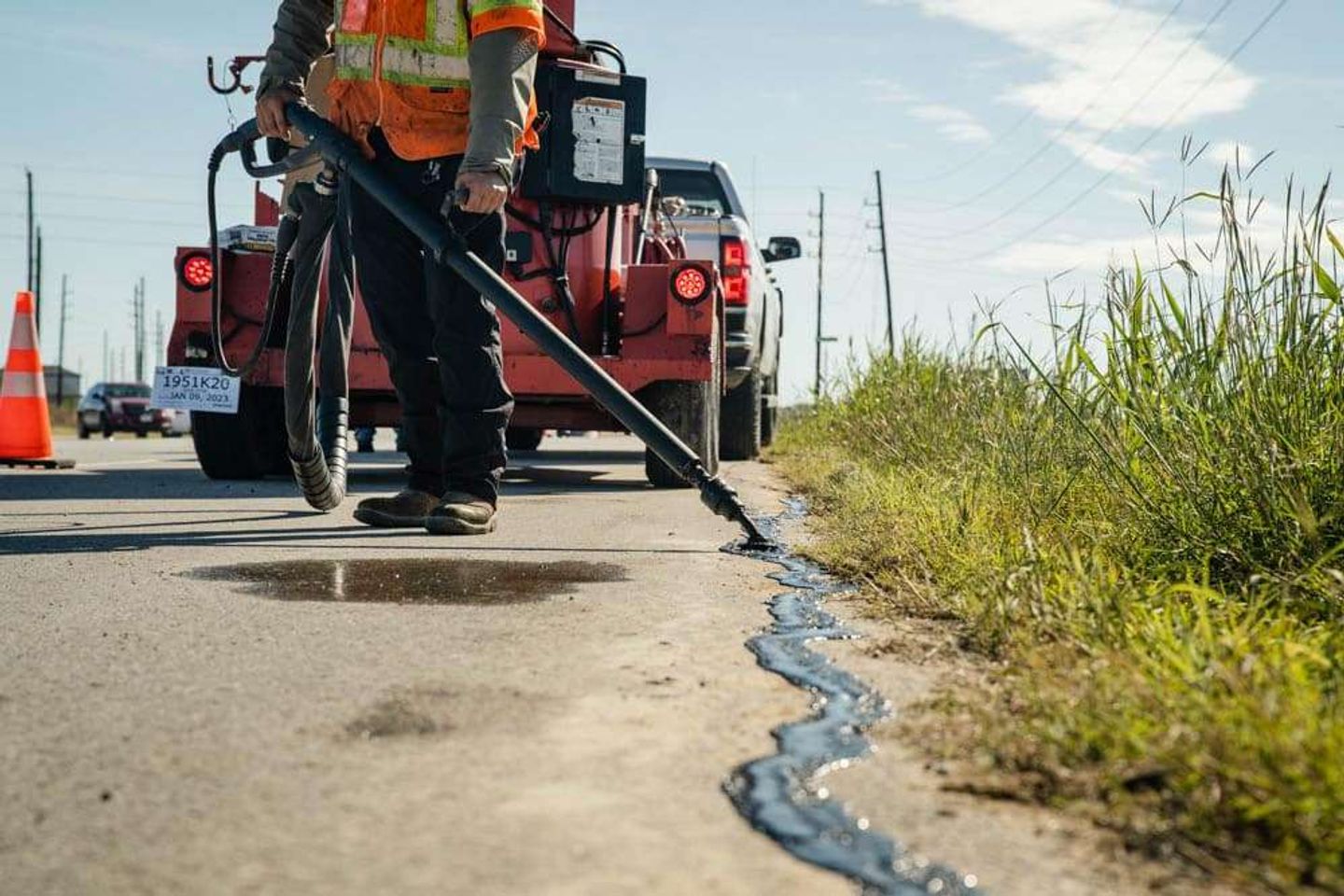 AAA Paving crew applying fresh sealcoat to a commercial driveway with a squeegee in the Houston area