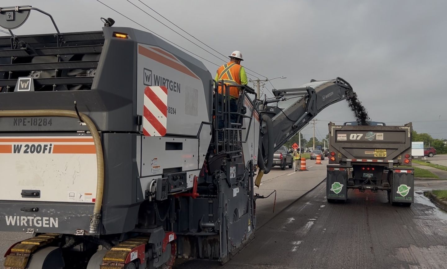 Close-up of an asphalt milling machine removing damaged pavement on an AAA Paving project