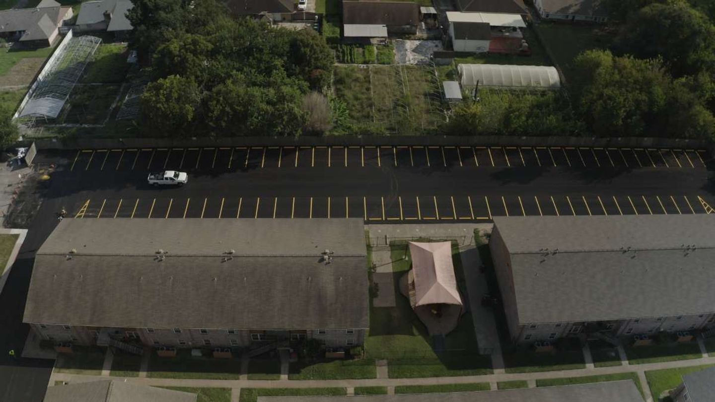 Aerial of a long parking lot with crisp fresh yellow stripes painted by AAA Paving in the Houston metro
