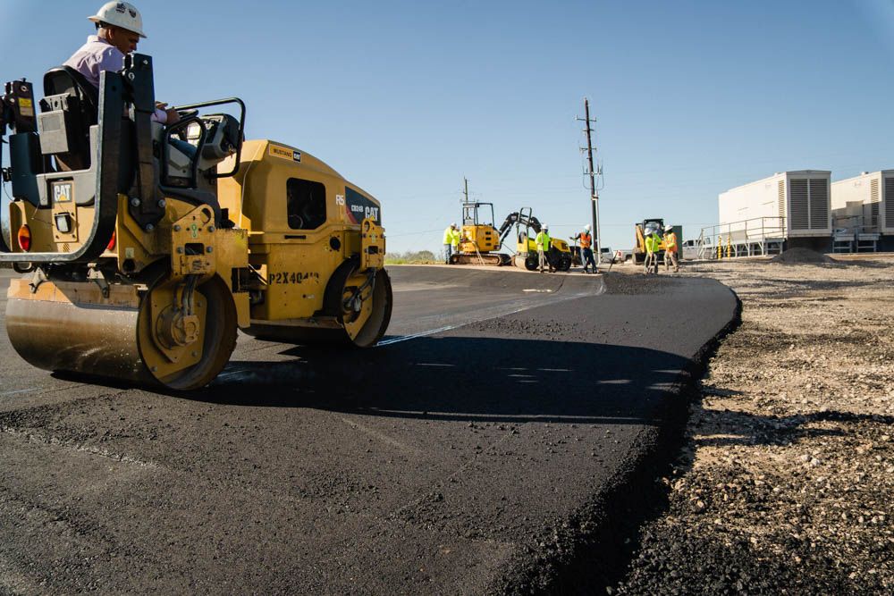 Workers on Asphalting paver machine during Road street repairing works. Street resurfacing. Fresh asphalt construction. Bad road