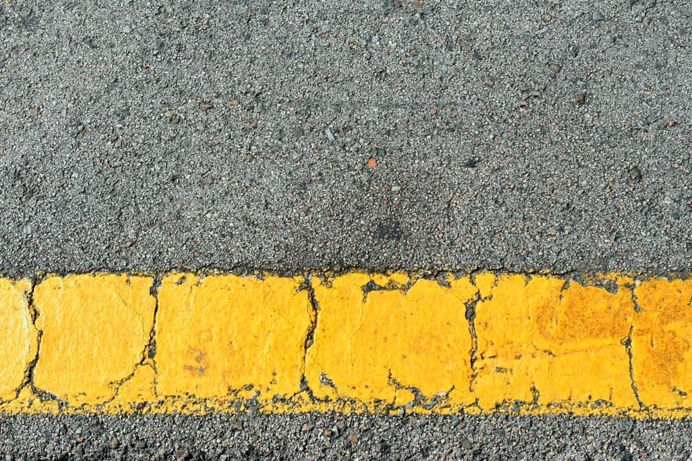 Yellow strip of old road markings on gray asphalt.
