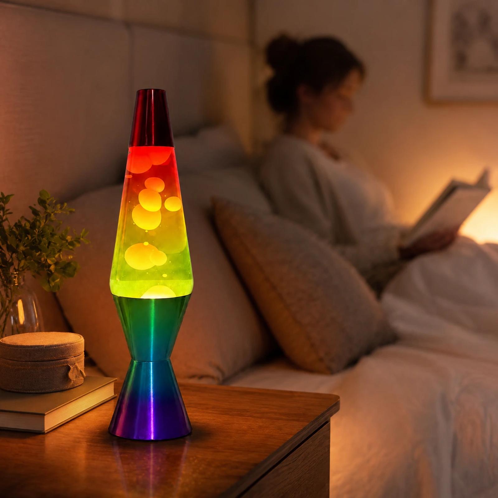 MX-3027R rainbow lava lamp glowing on a bedroom side table with warm ambient light and a blurred person reading in the background