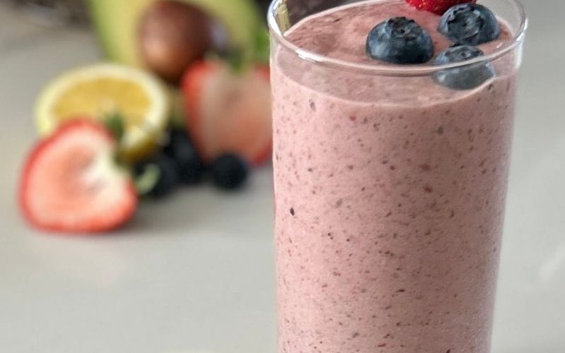 A pink berry smoothie topped with fresh fruit