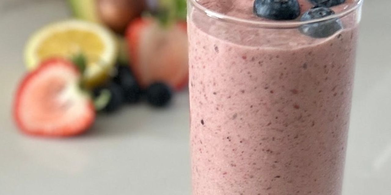 A pink berry smoothie topped with fresh fruit