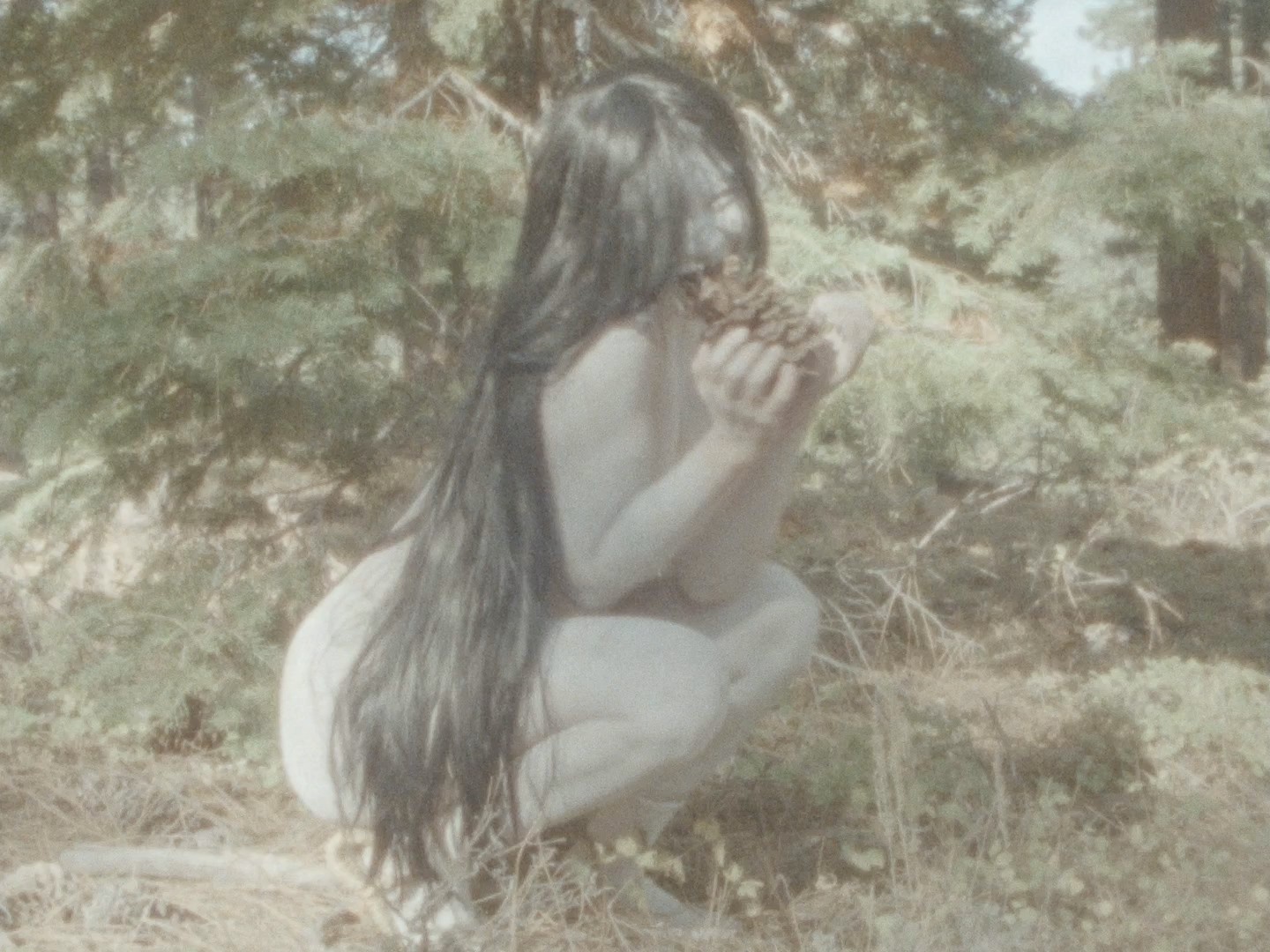 A crouching person with long black hair.