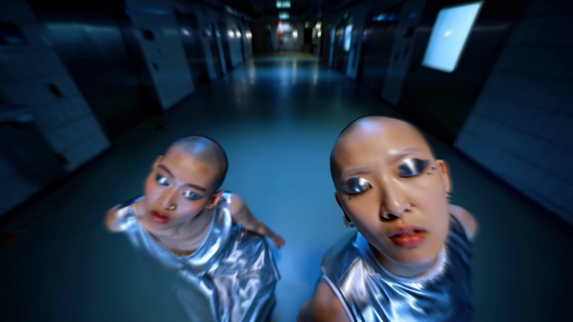 two figures in silver dresses in a corridor.