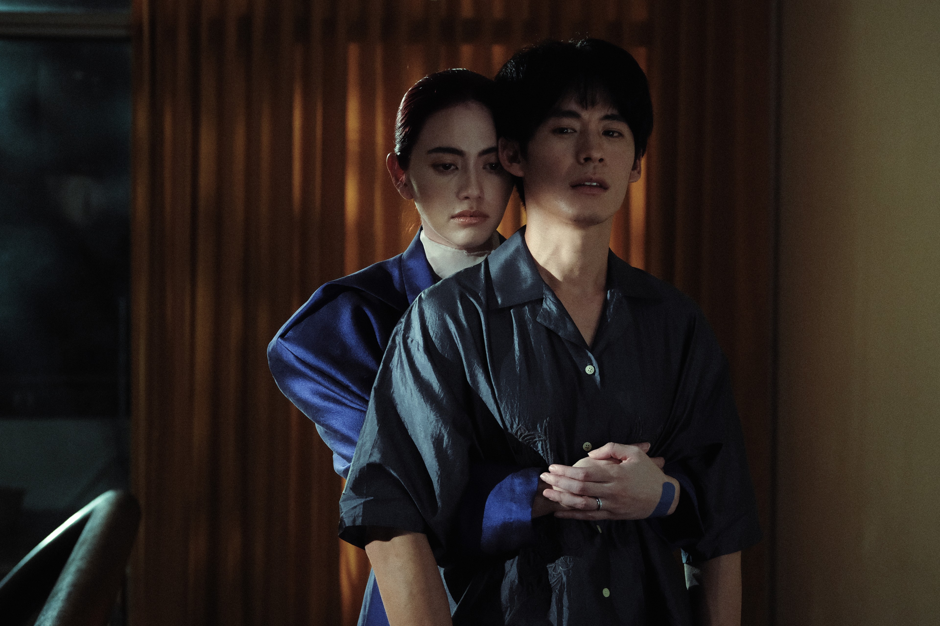A person standing behind another person and holding them around the waist indoors.