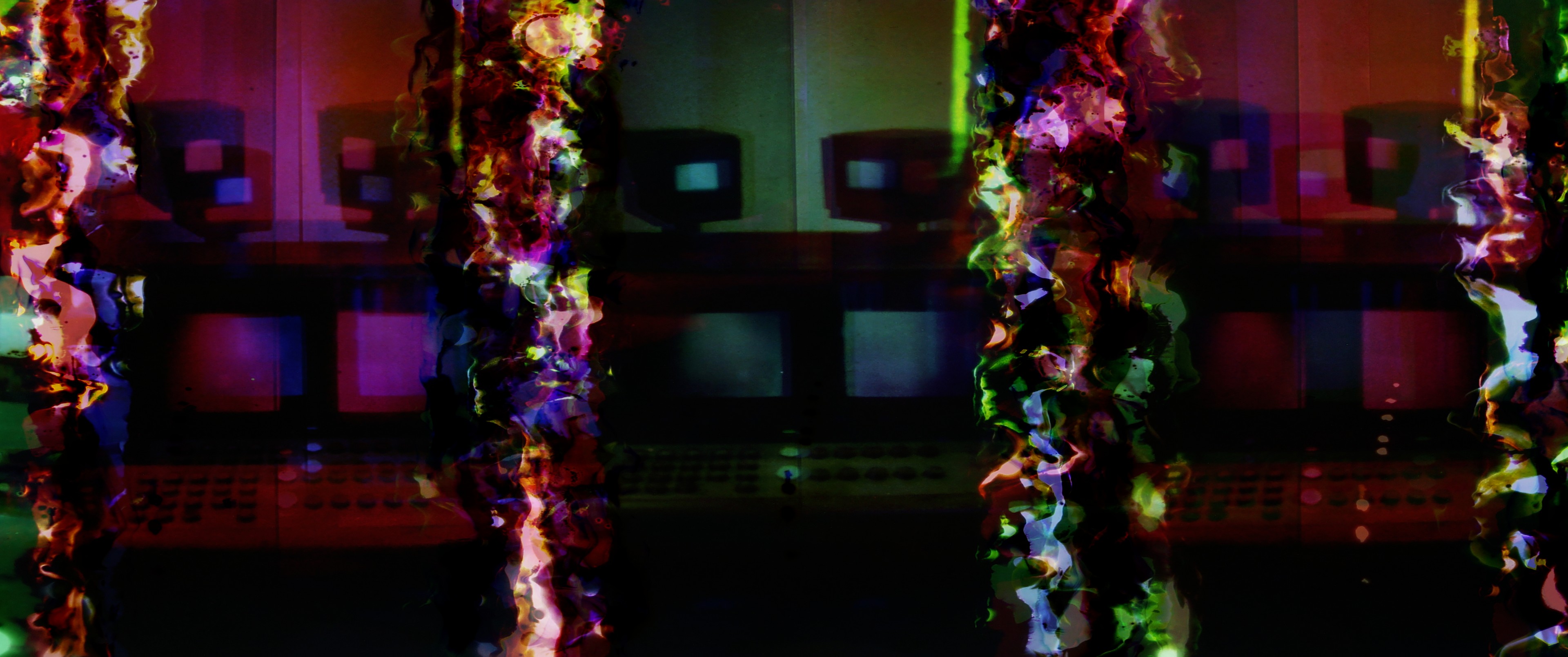 An abstract, mirrored composition of glowing vertical forms layered over rows of dark screens in vivid red, green and purple tones.