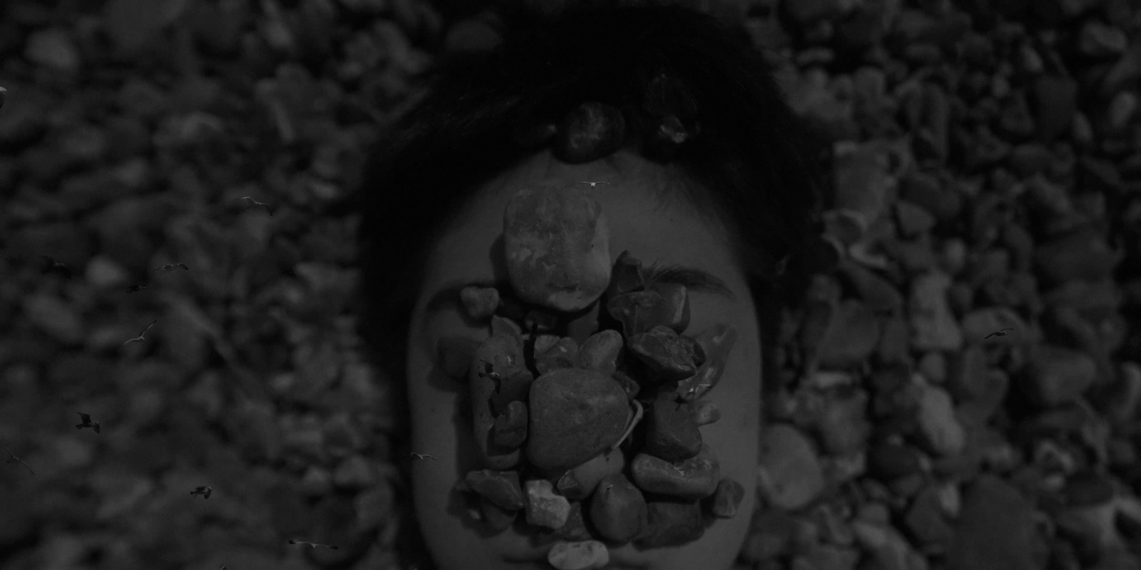 A person's face obscured by a stack of rocks.