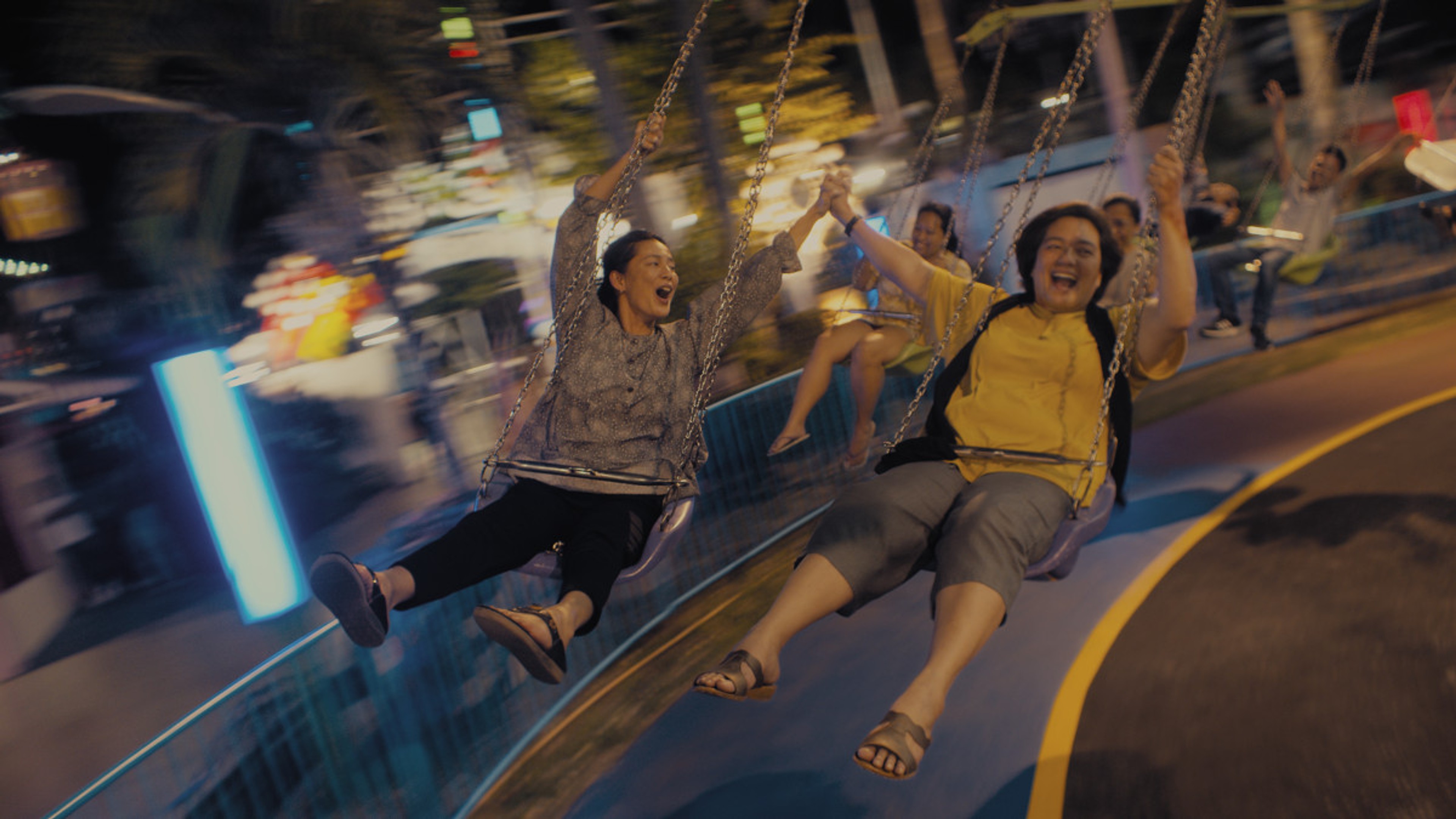 Two women scream on a fairground ride.