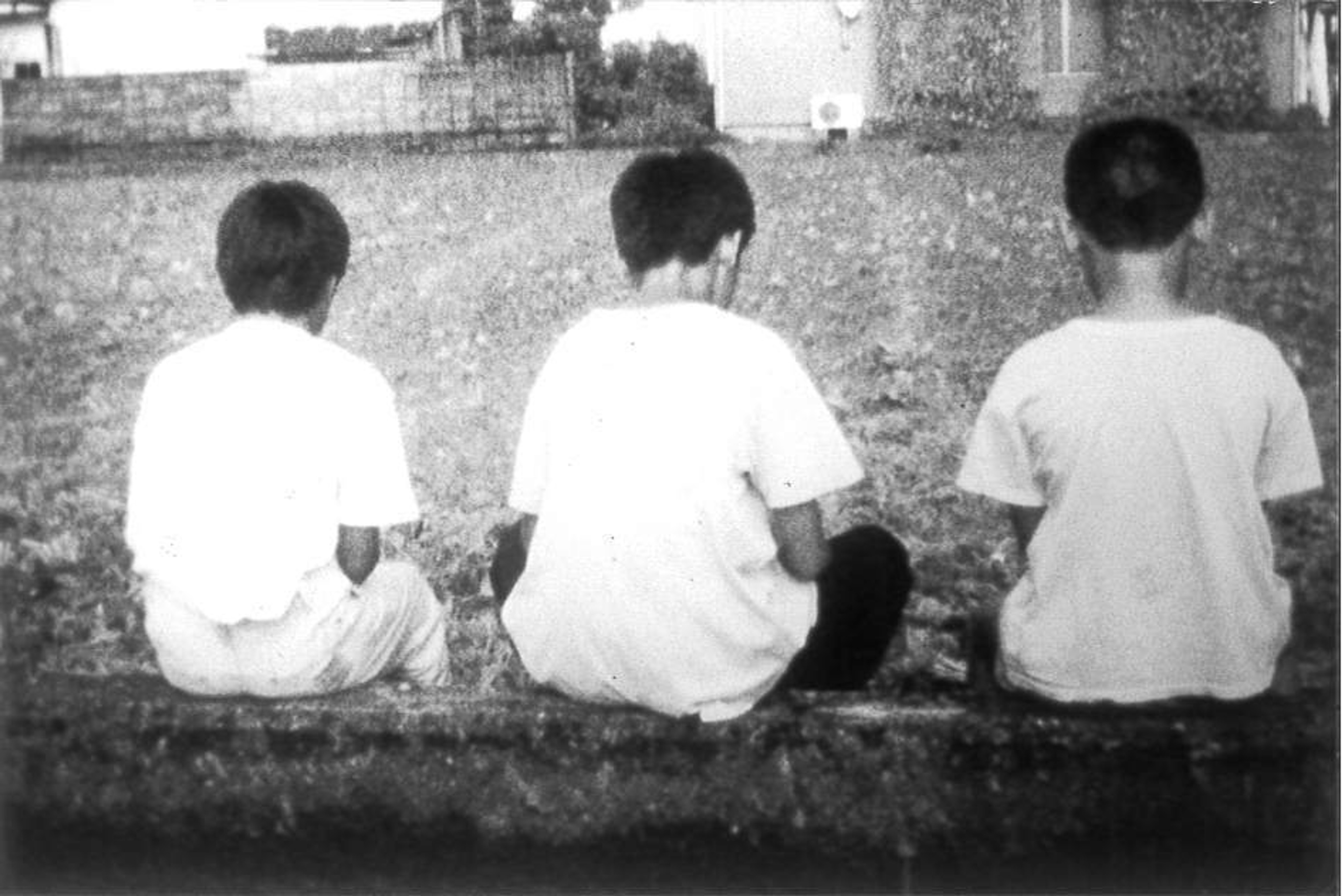 Three boys sit in a row with their backs turned away.