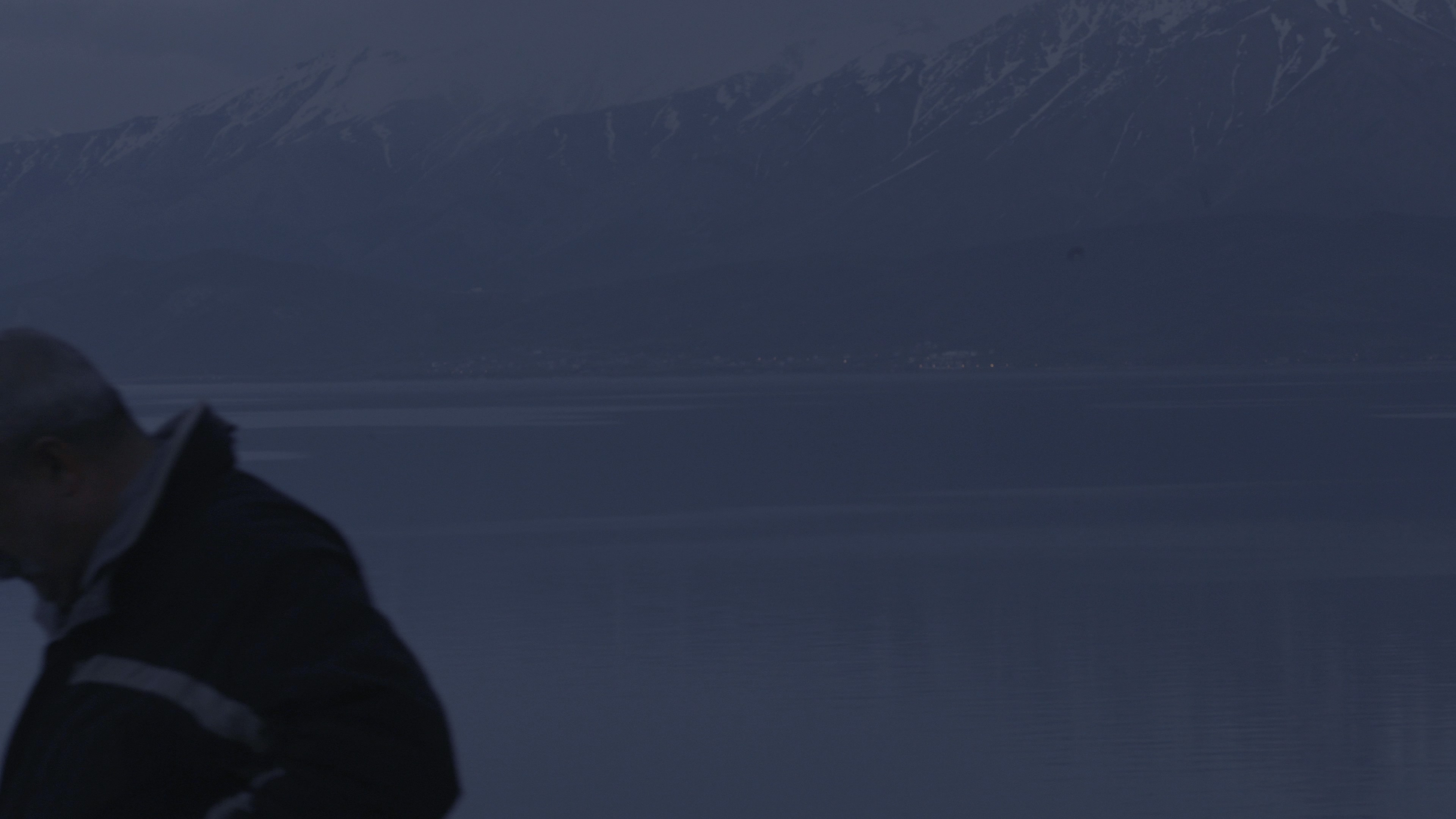 Blurry outline of snow topped mountain with a figure turning away in the foreground.
