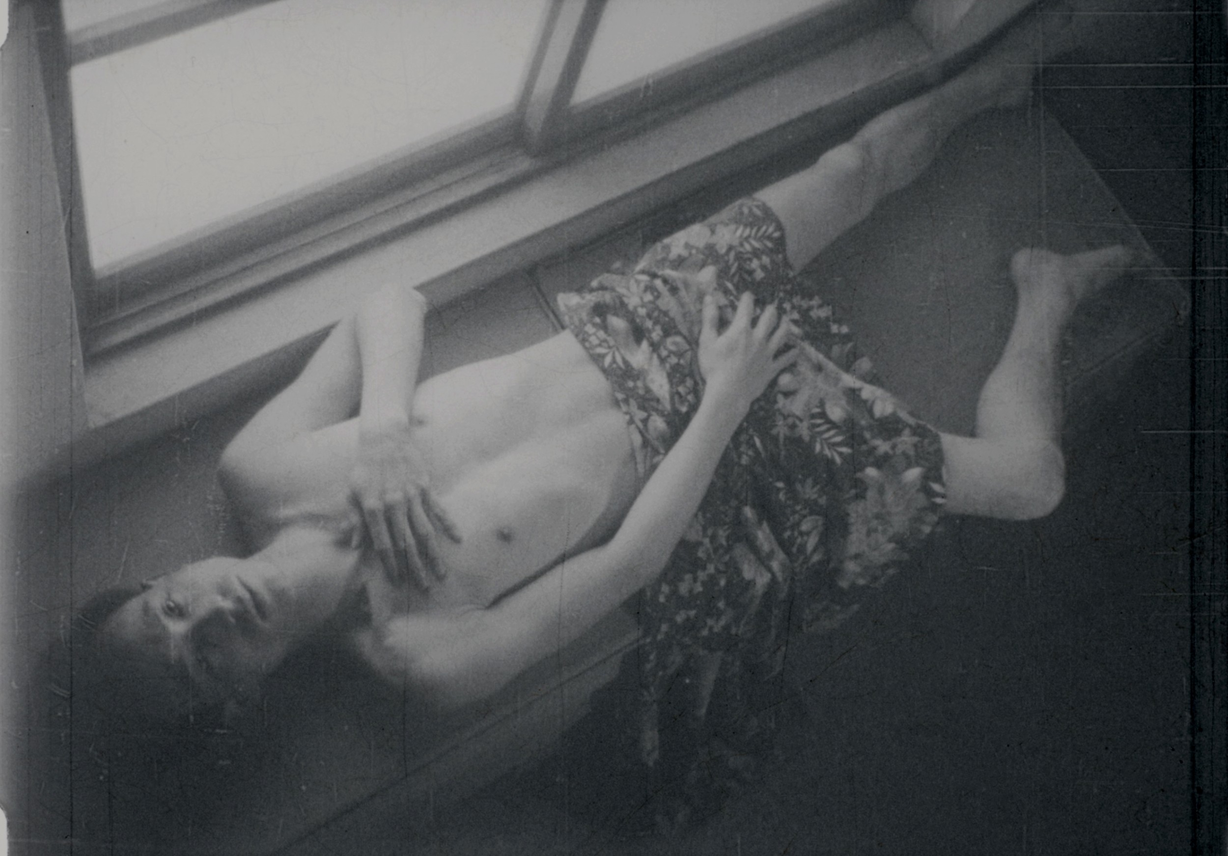 A man lying down with a hand over his crotch.
