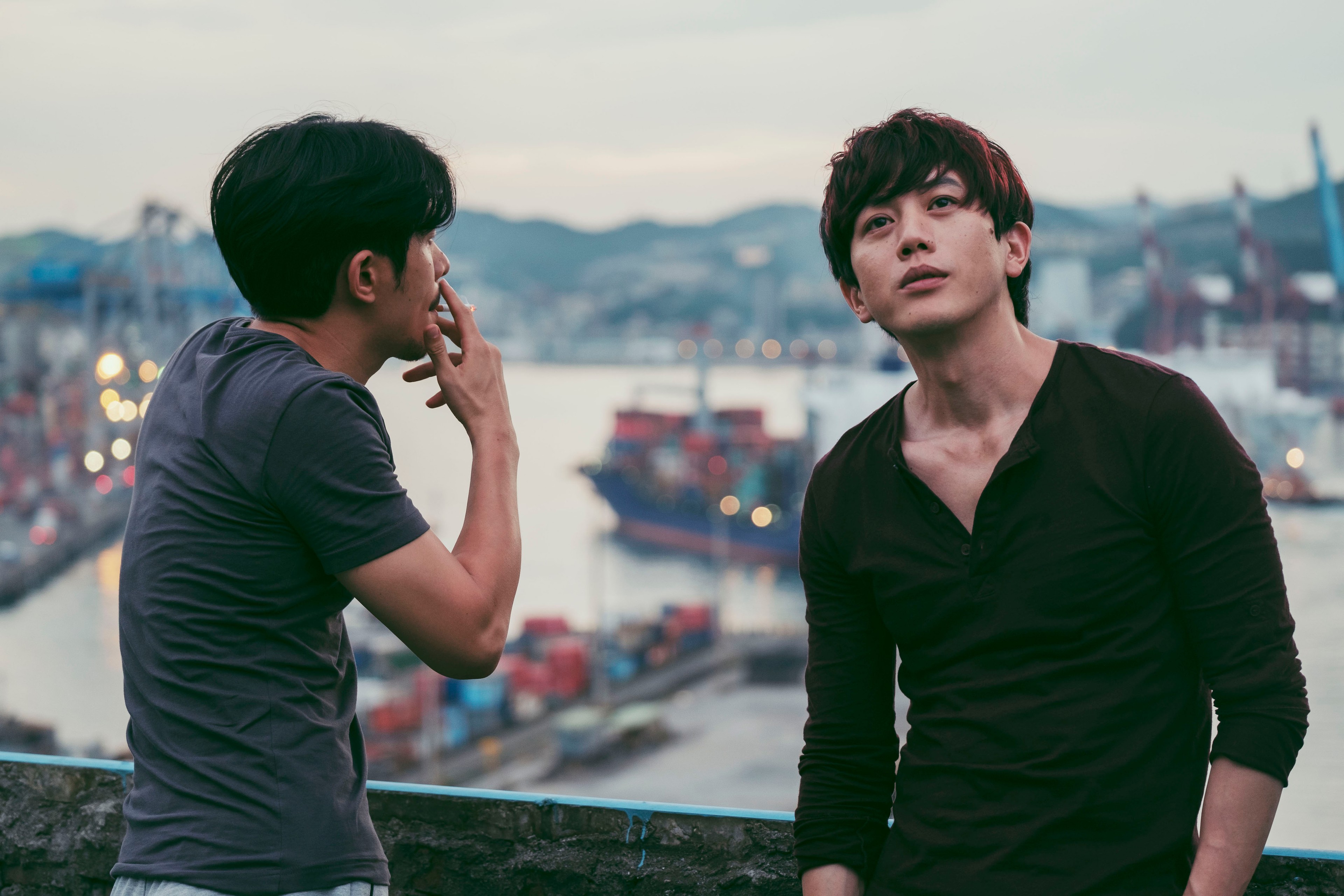 Two men smoking against the backdrop of a harbour.