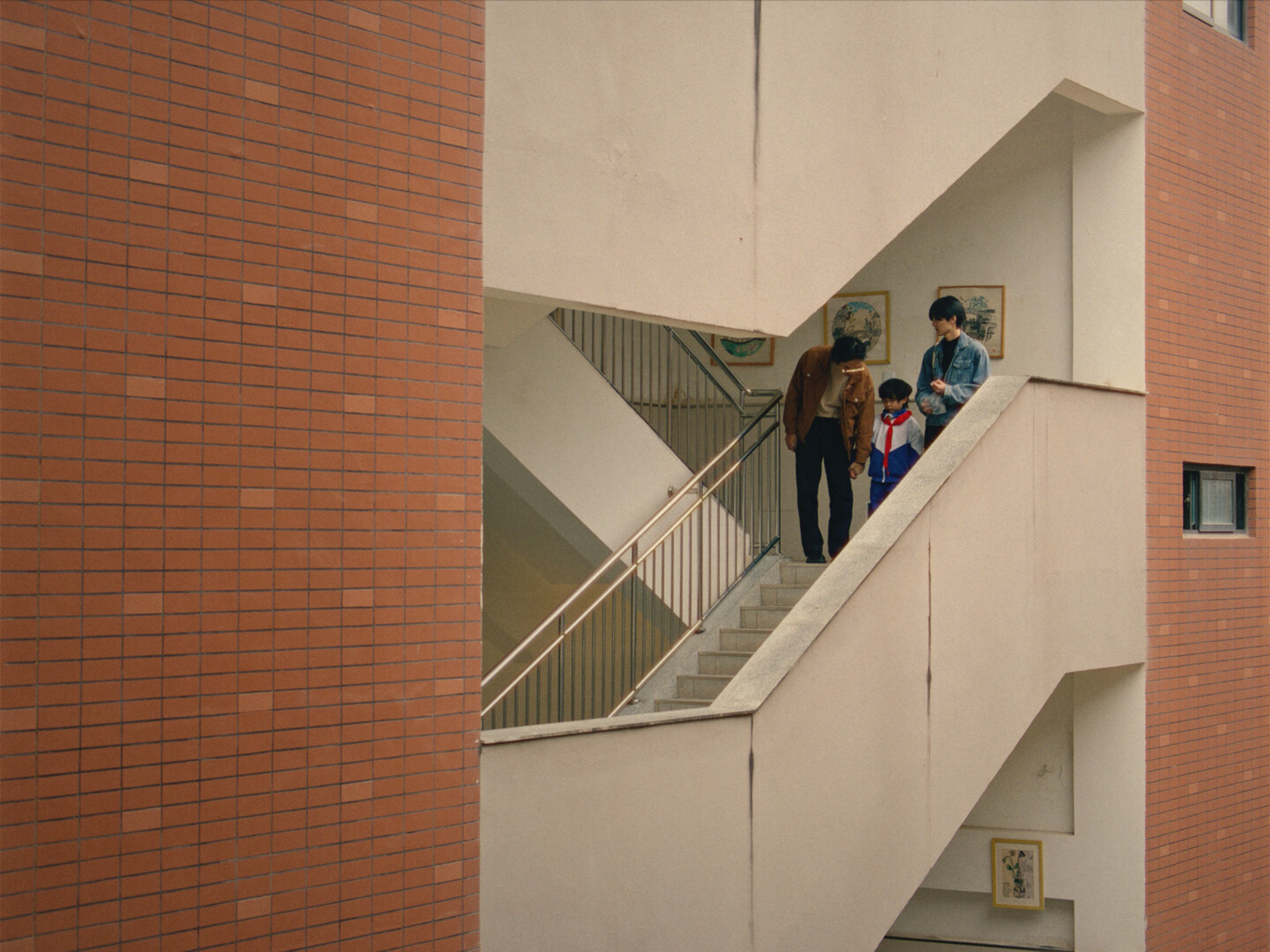 Two men and a young boy go down a staircase.