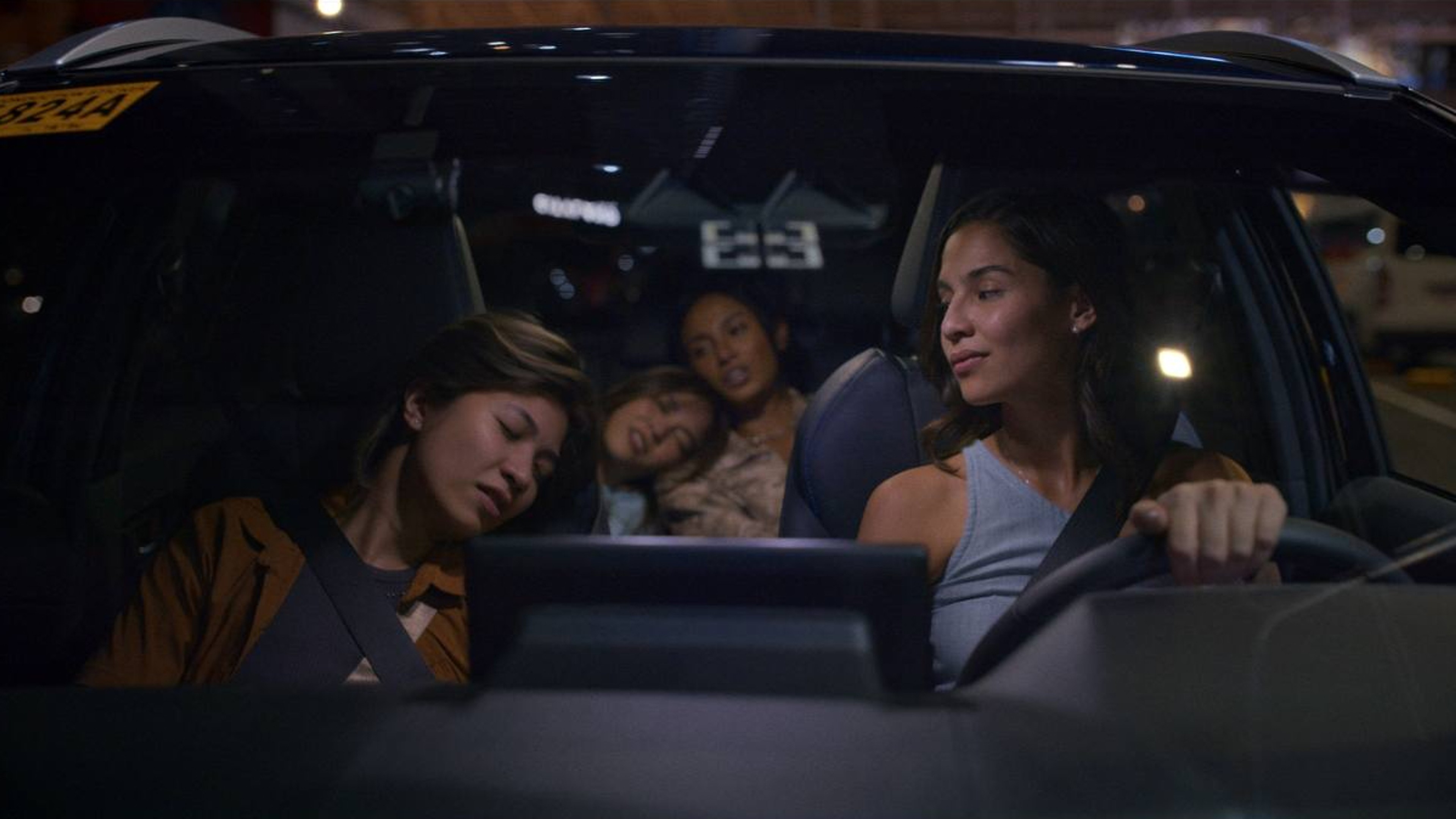 A woman driving at night with several passengers asleep in the car.