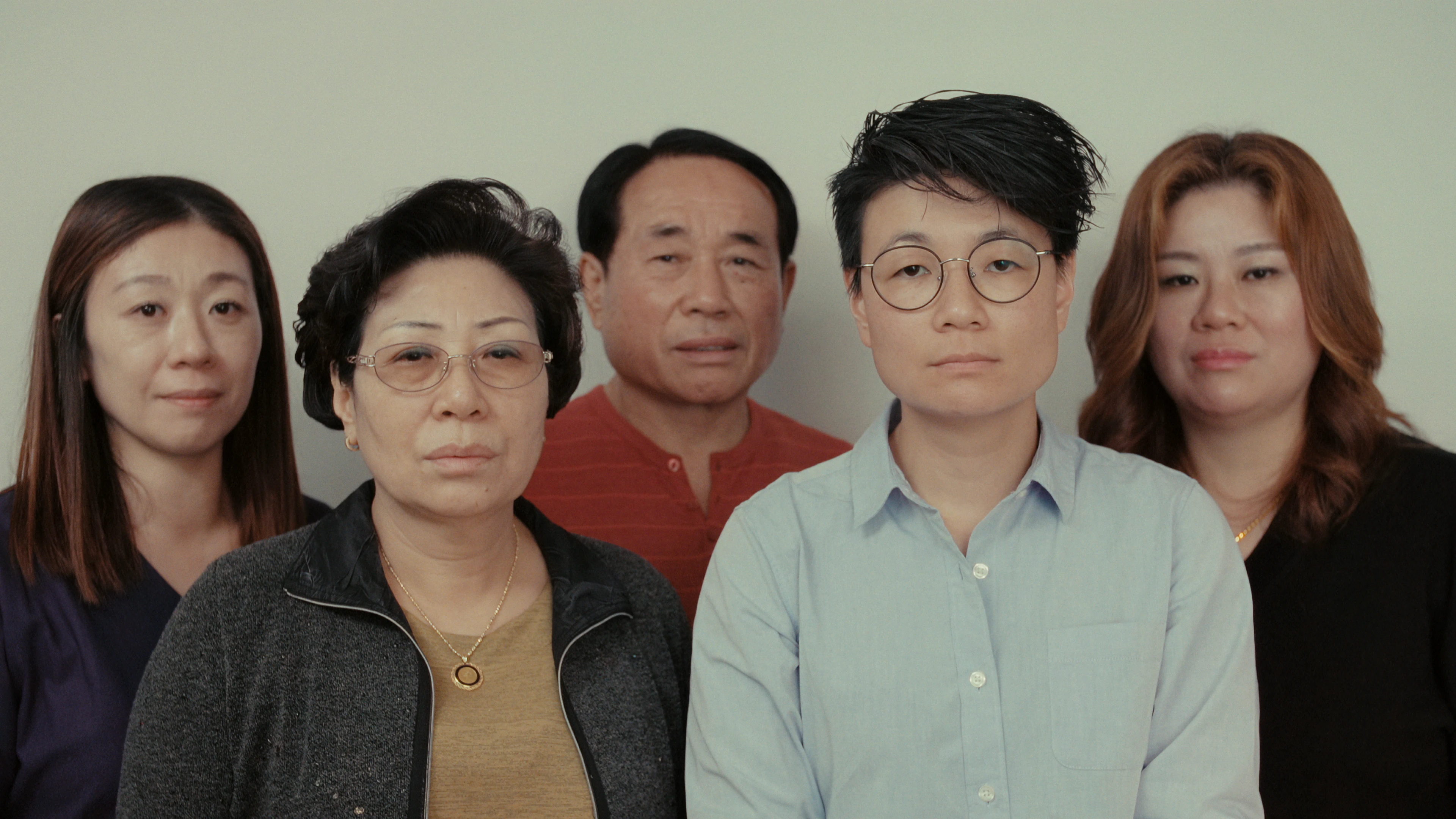 Five people posing together for a group portrait against a plain background.