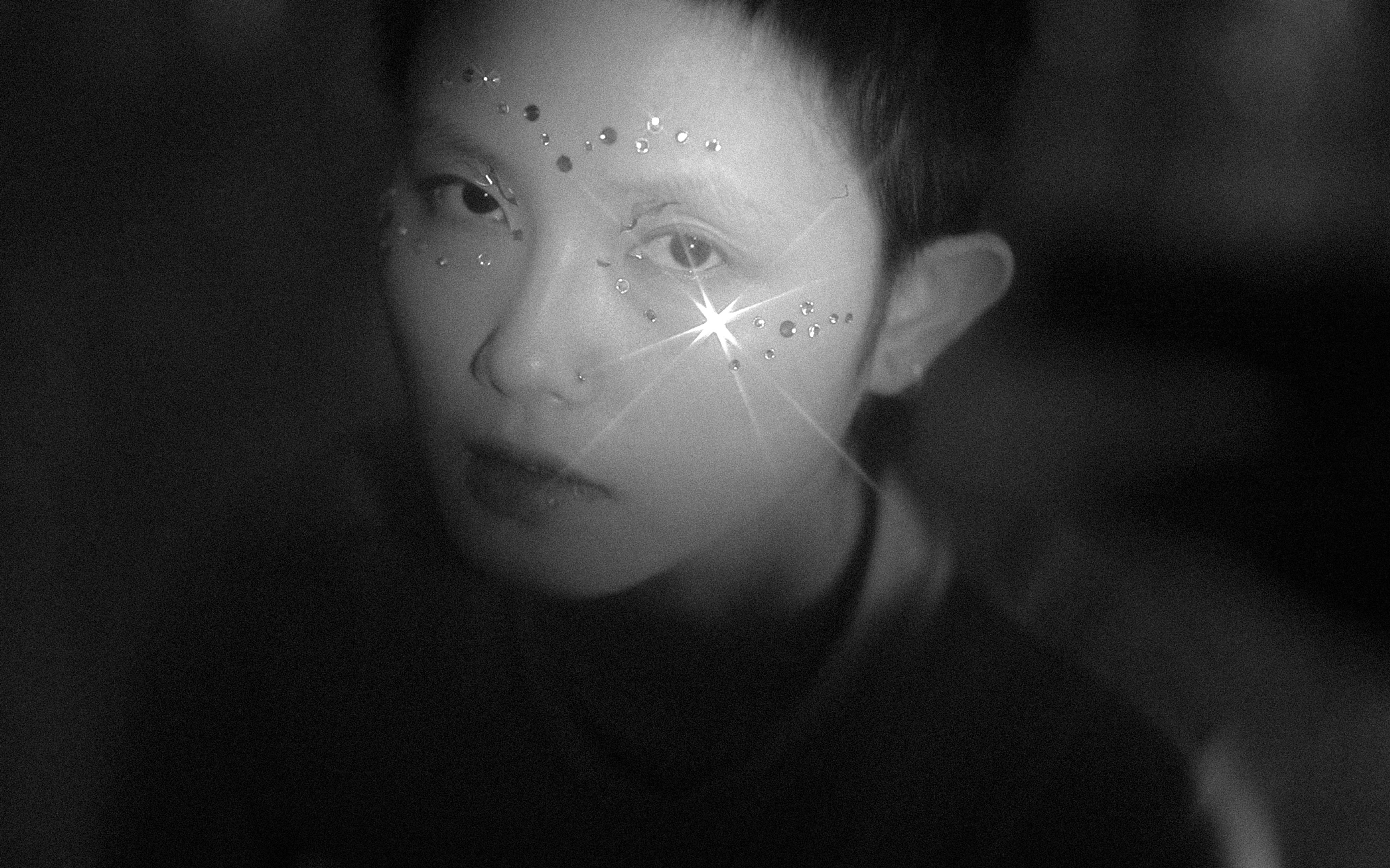 A person's face sparkles with jewels.