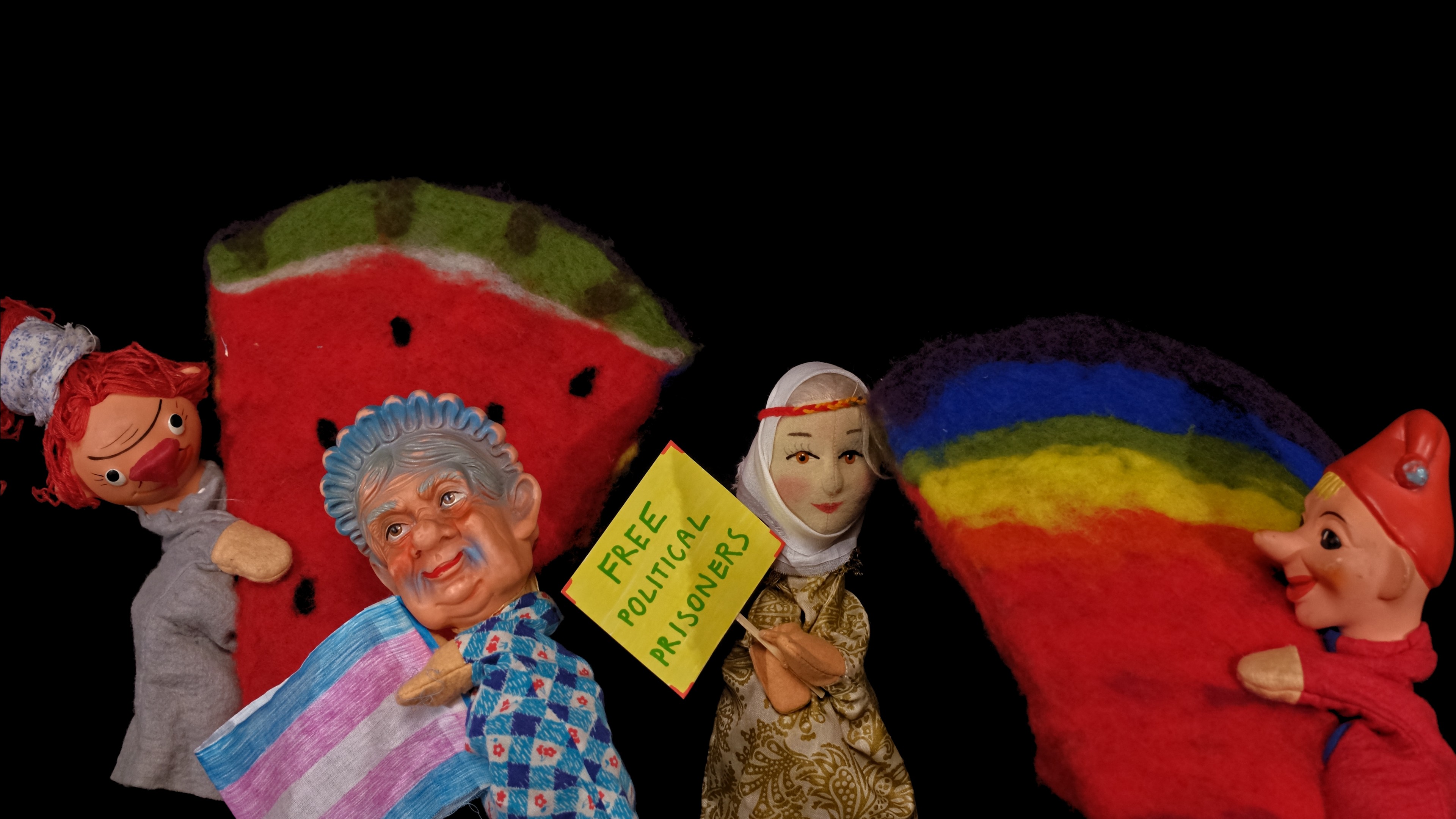 Four puppets hold watermelons and a trans pride flag.