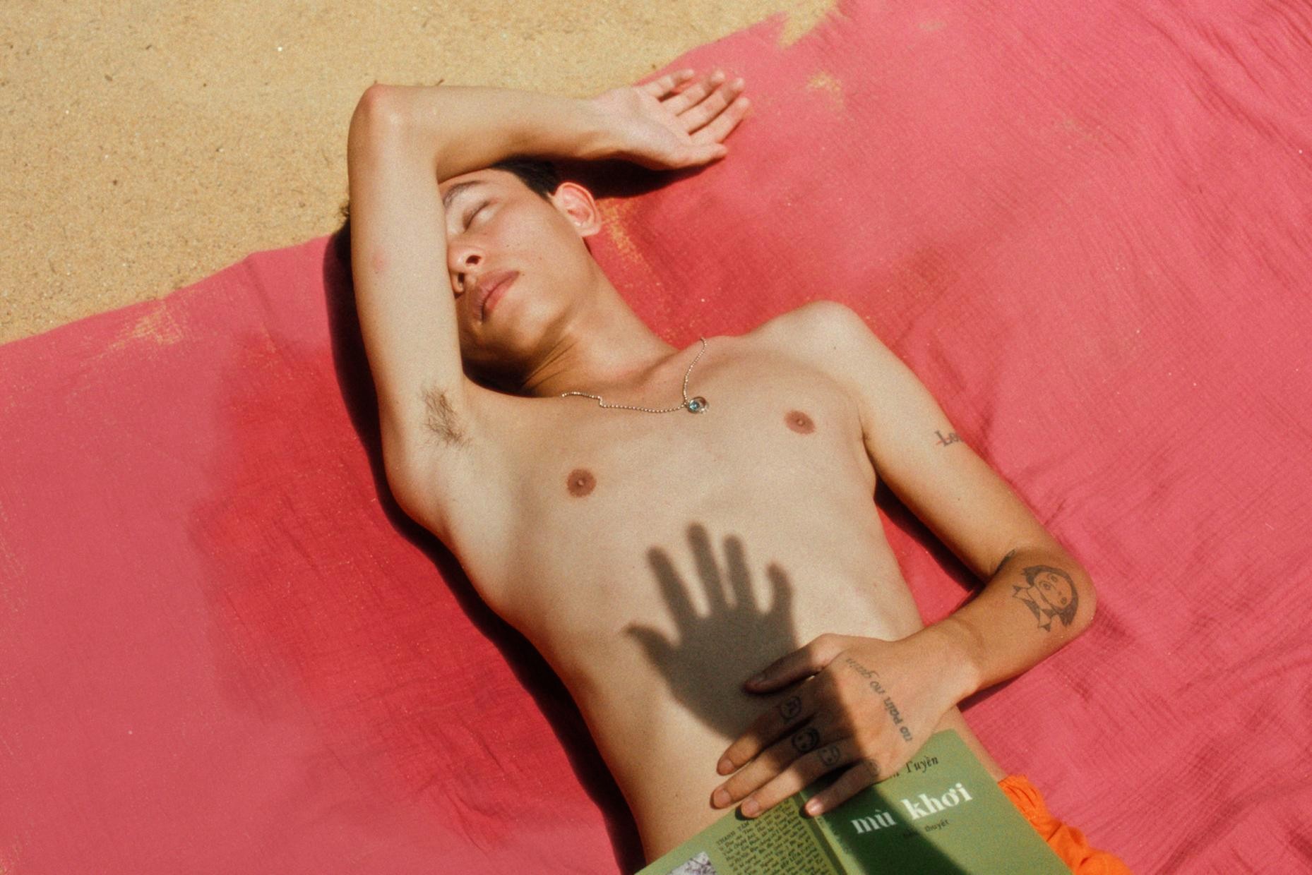 The shadow of a hand overlaid over a man lying on the ground.