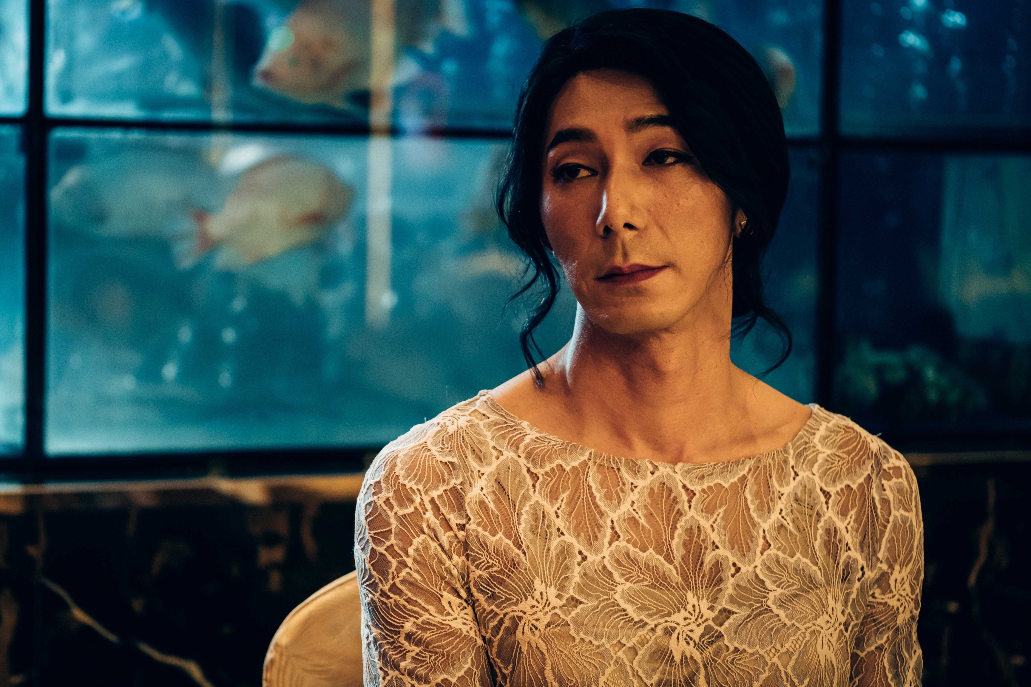 A woman wearing a white dress against the backdrop of an aquarium.