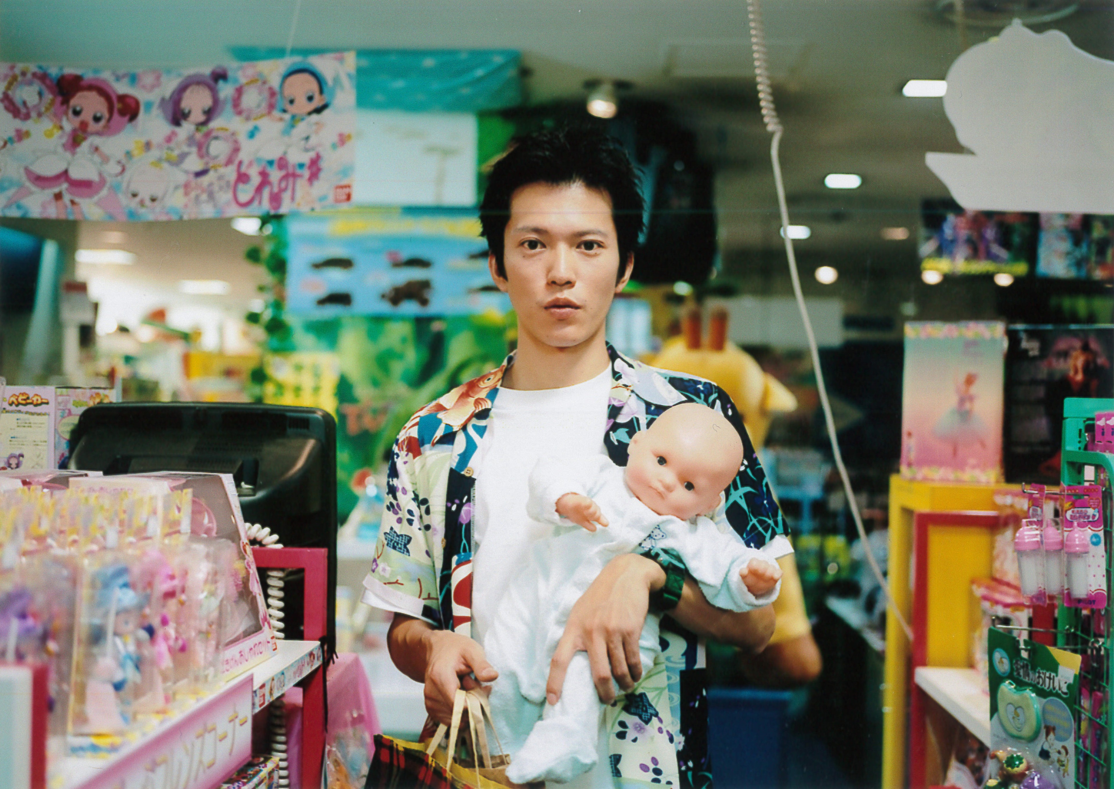 A man holding a toy baby in a store.