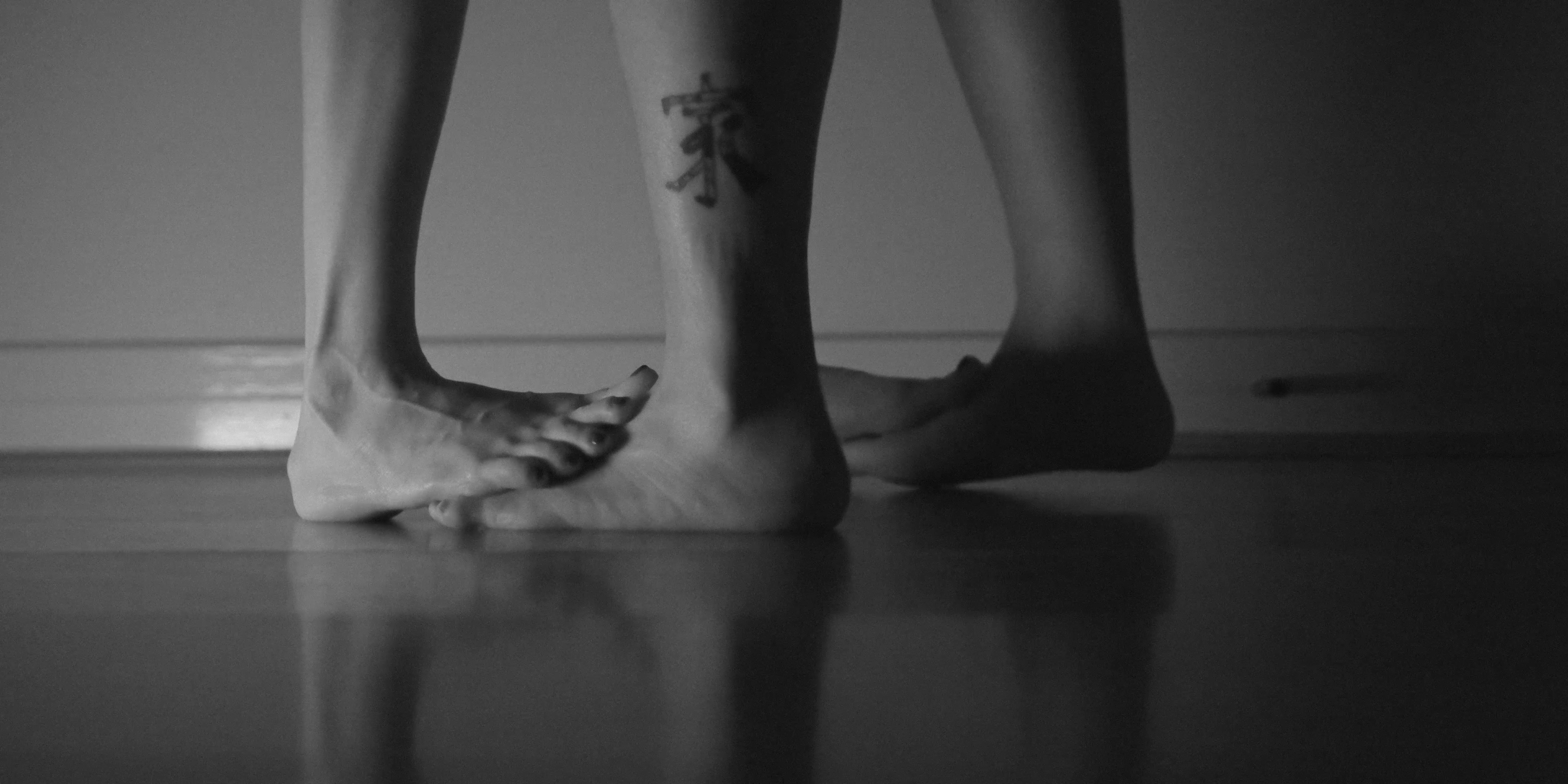 A pair of feet stand on top of another pair of feet.