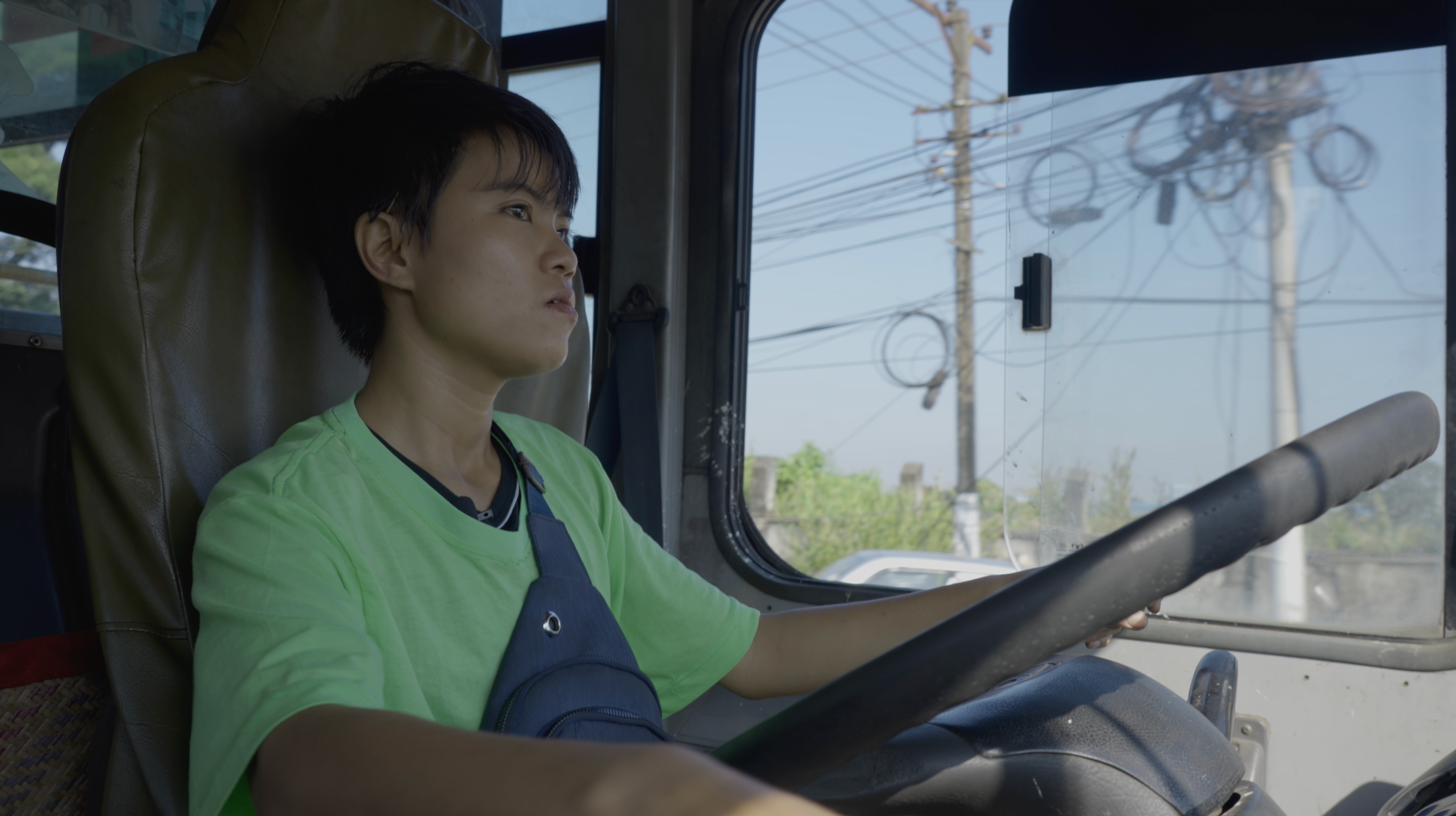 A person wearing a green shirt holding a steering wheel.