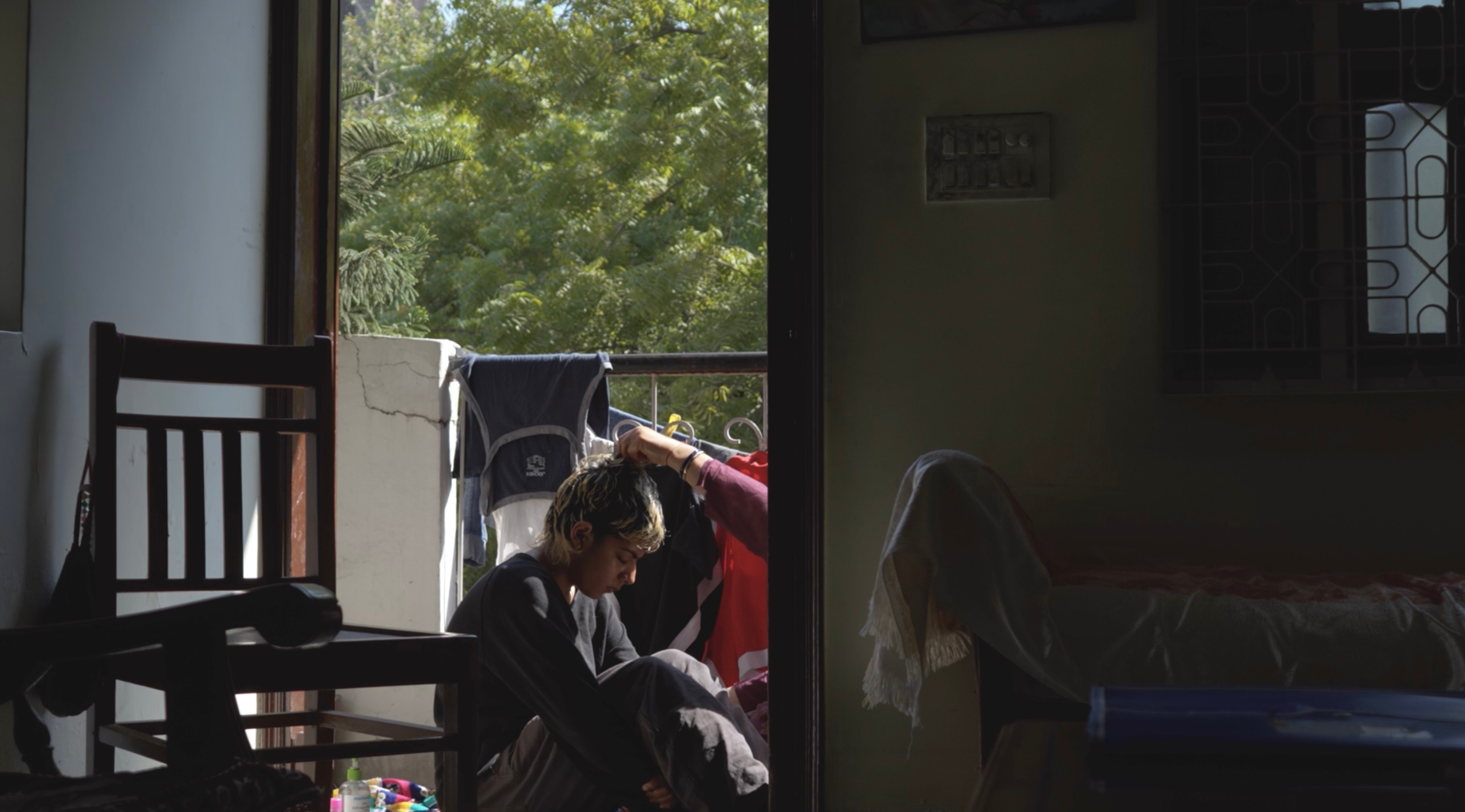A person hugs their knees in a door frame.