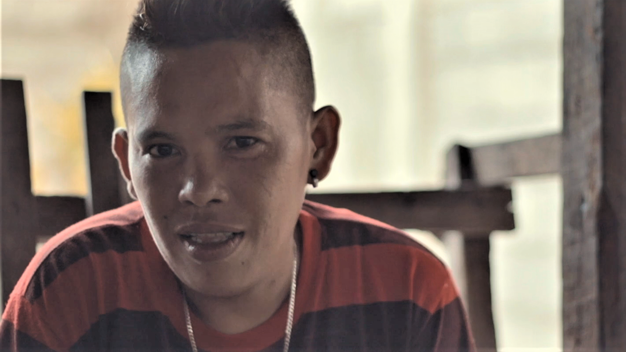 A person wearing a black and red striped shirt looks into the camera.