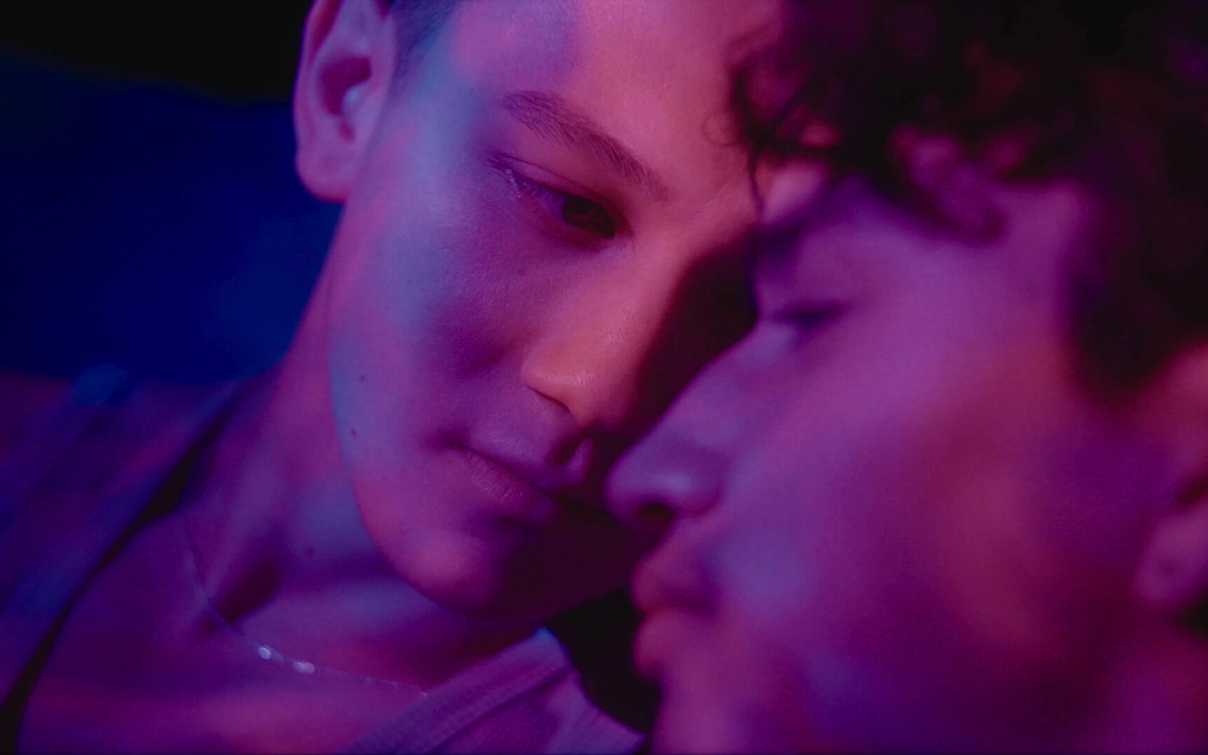 two people bathed in purple light gaze at each other.