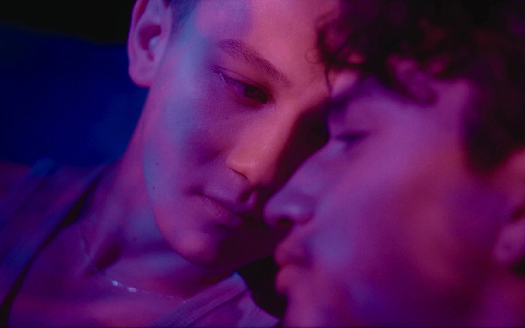 two people bathed in purple light gaze at each other.