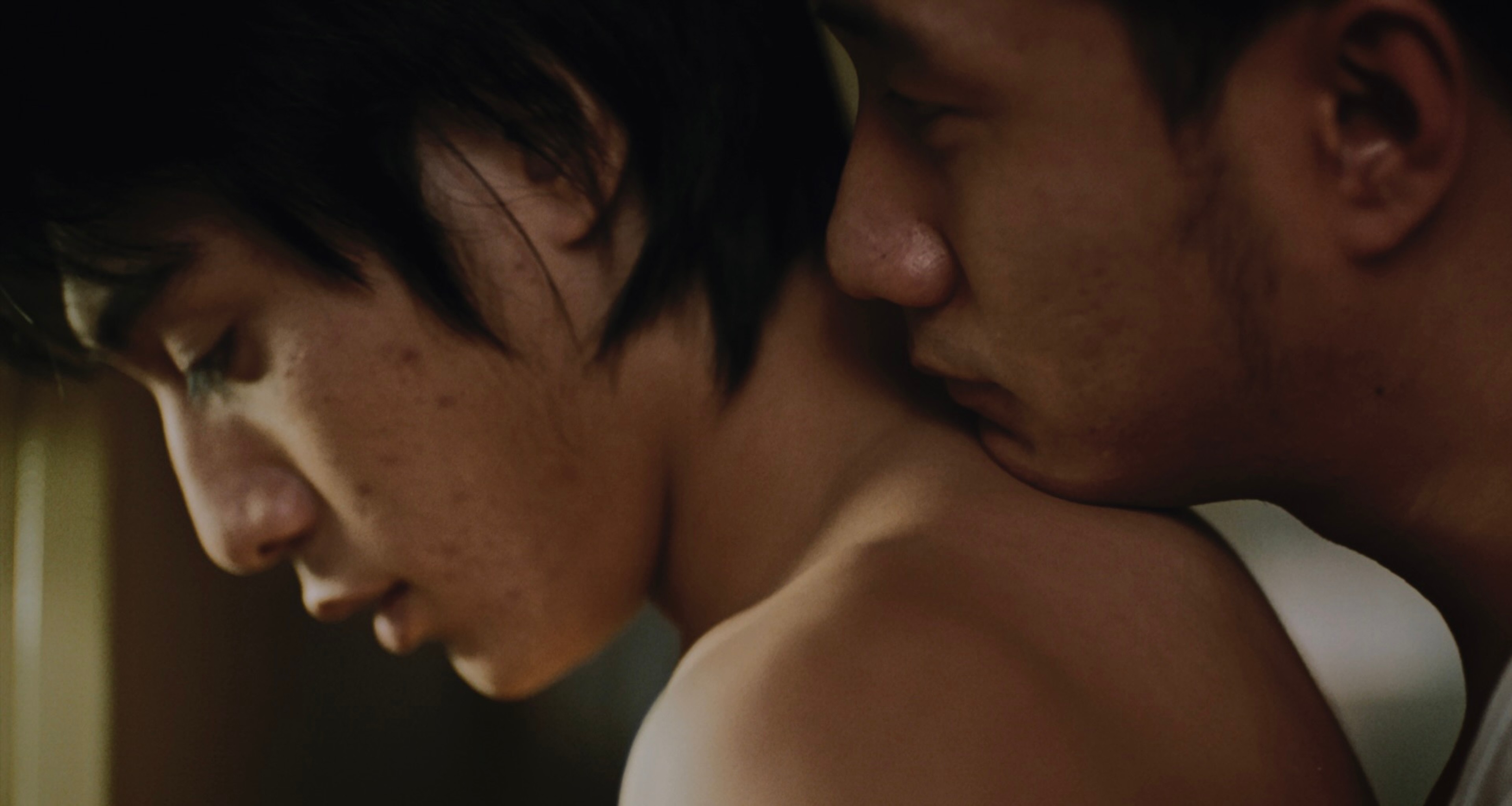 A man kisses another man's neck.