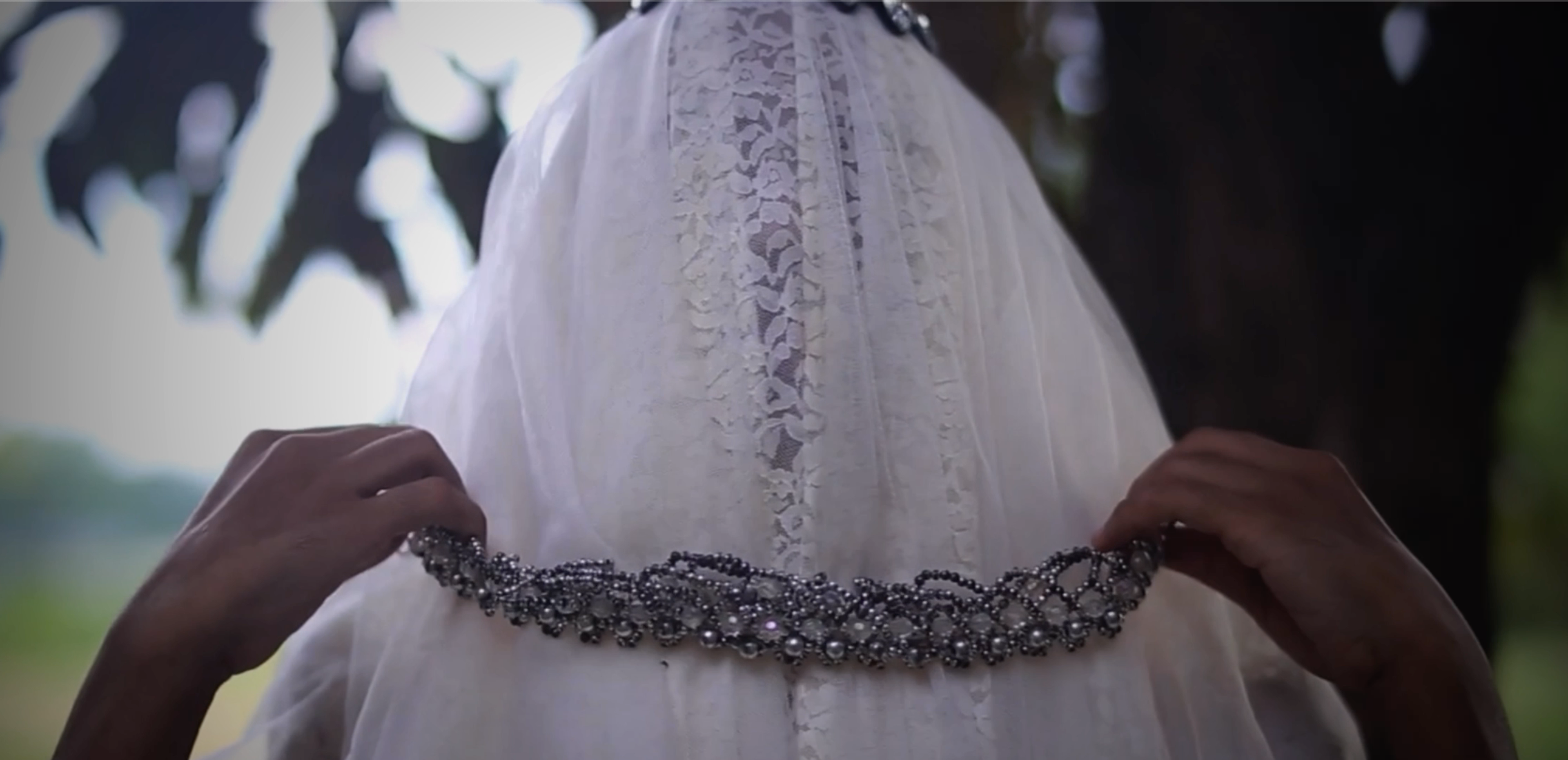 A person wearing a veil with a chain necklace.