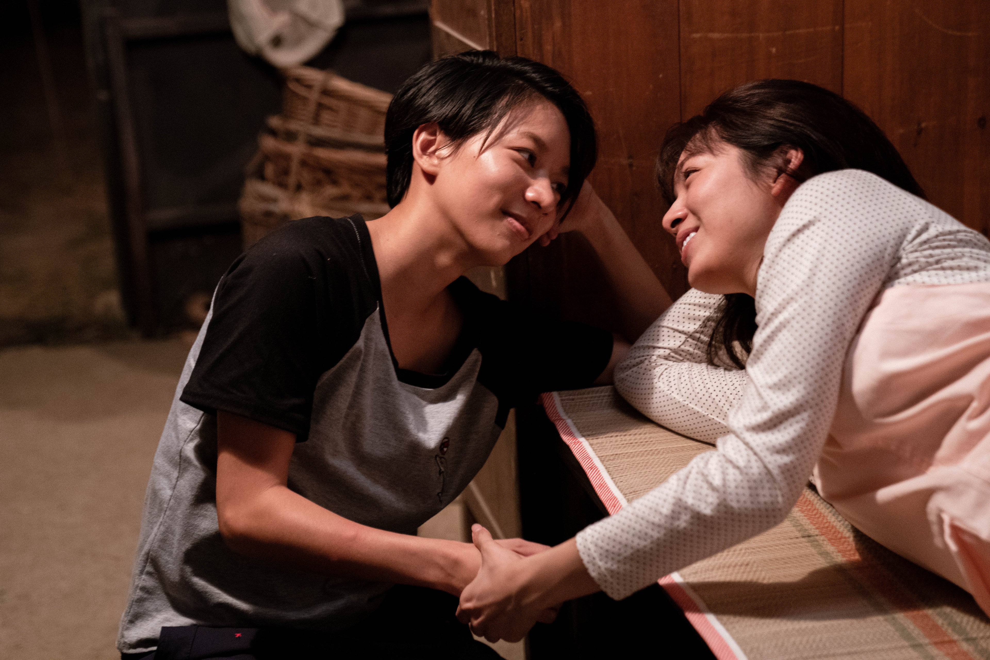 Two women hold hands and gaze into each other's eyes.