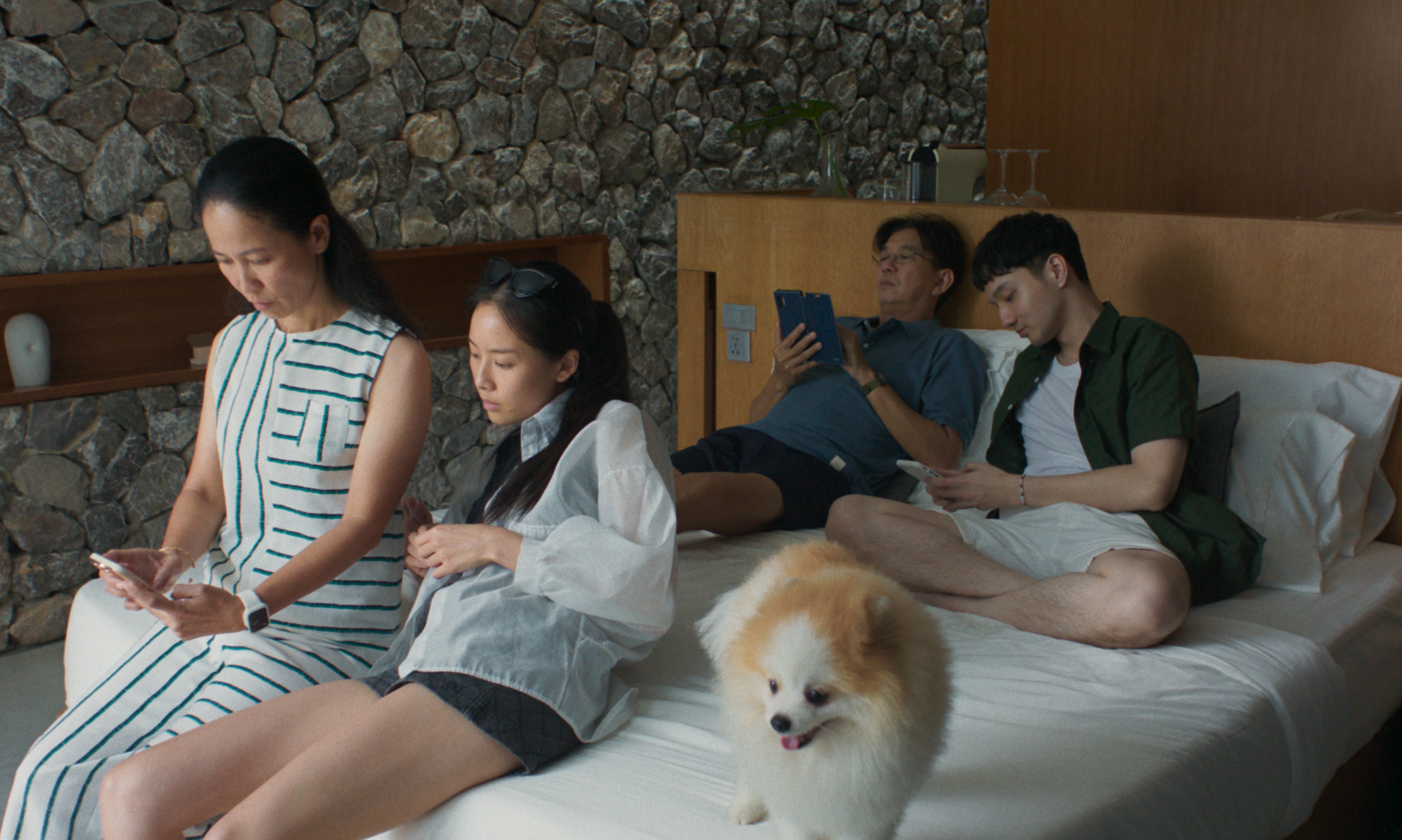 Four people and a dog on top of a bed.
