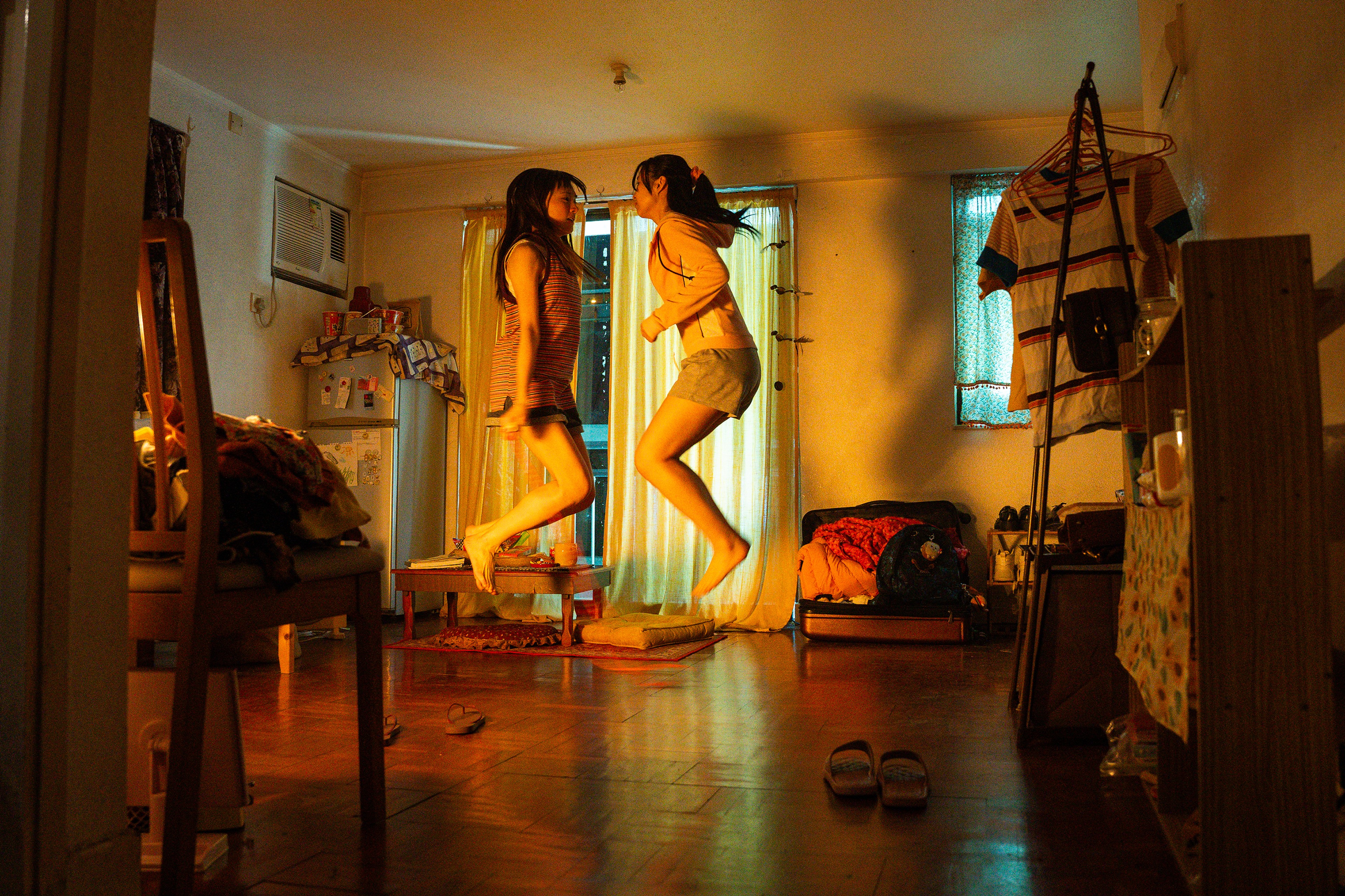 Two girls jump facing each other.