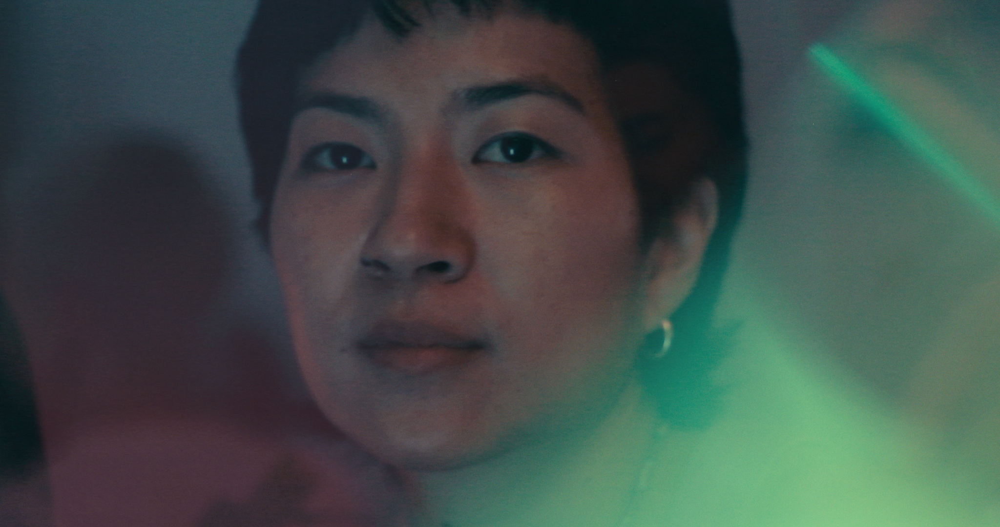 A person's face partially lit with green light.