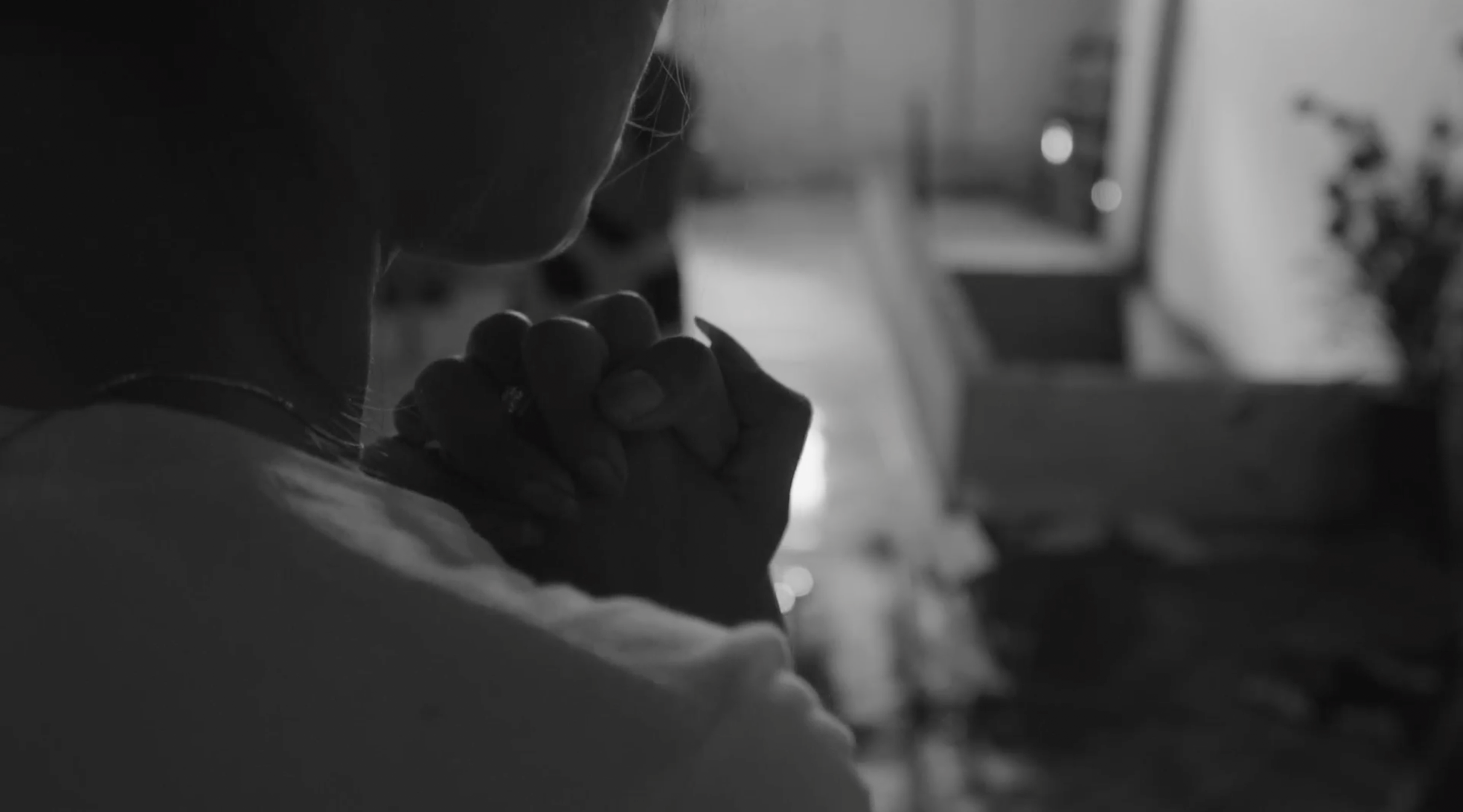 A person clasps their hands in prayer.