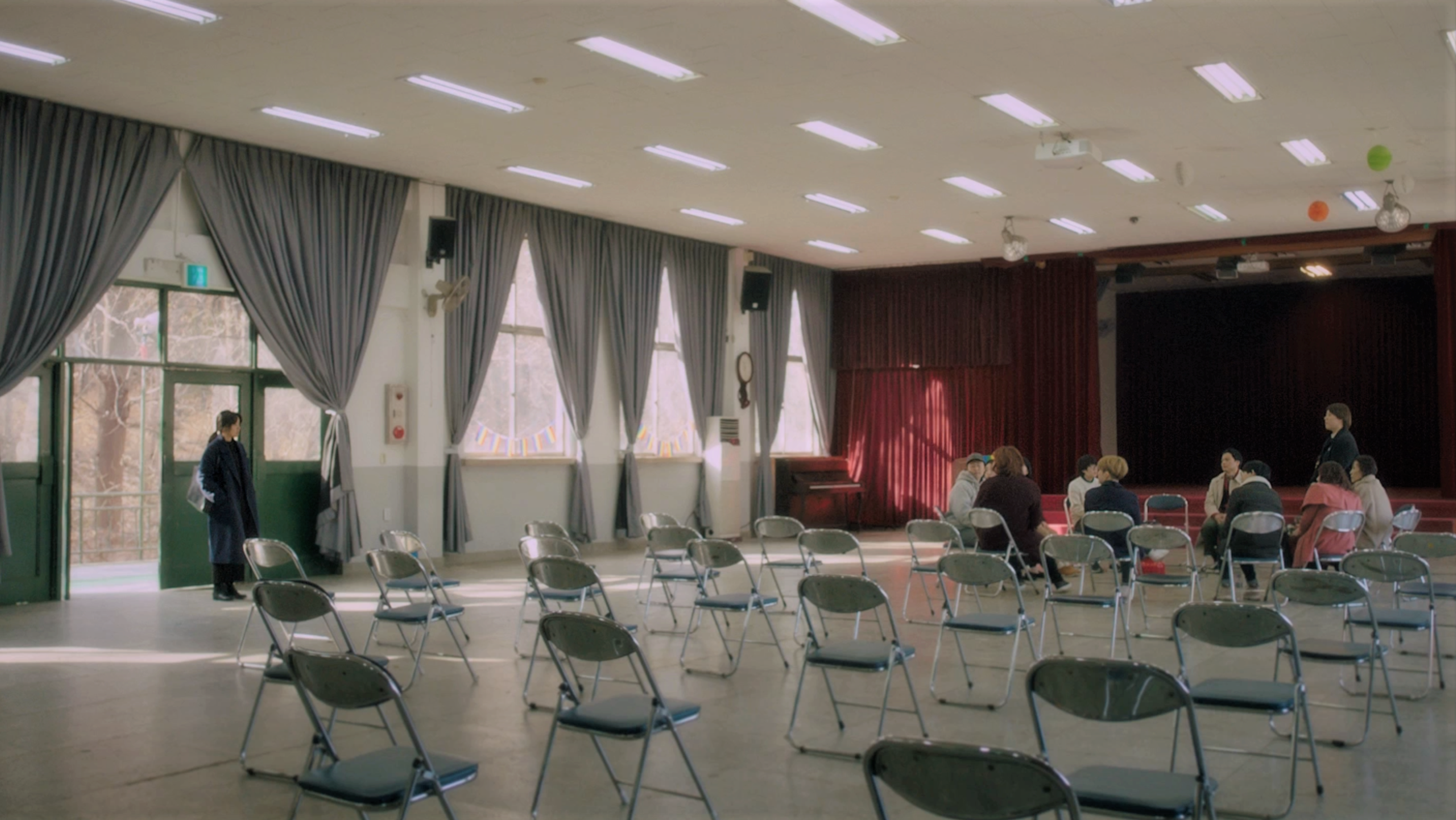 A room full of chairs with a few people sitting in a circle on them.