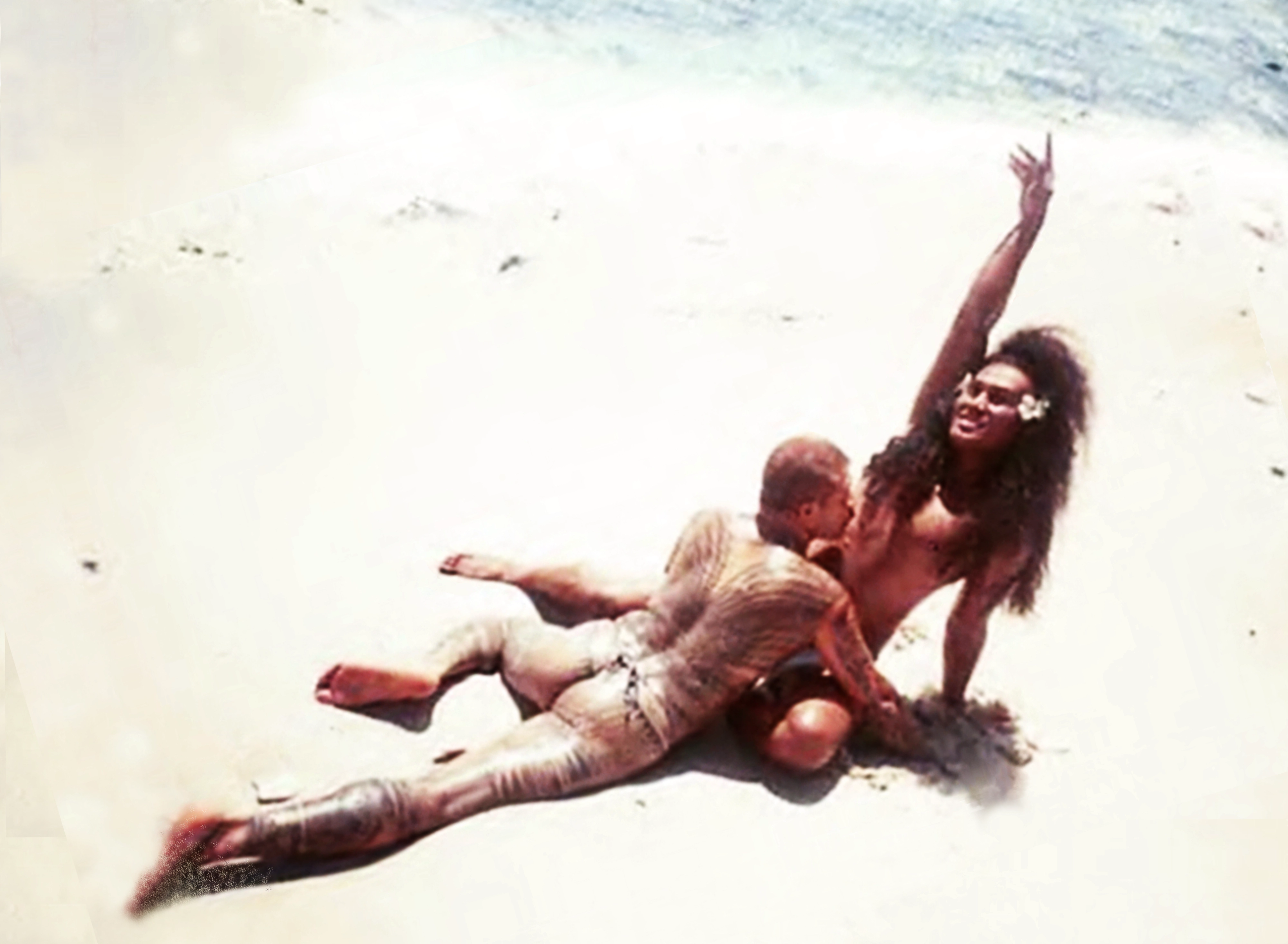 Two figures embrace on a beach.