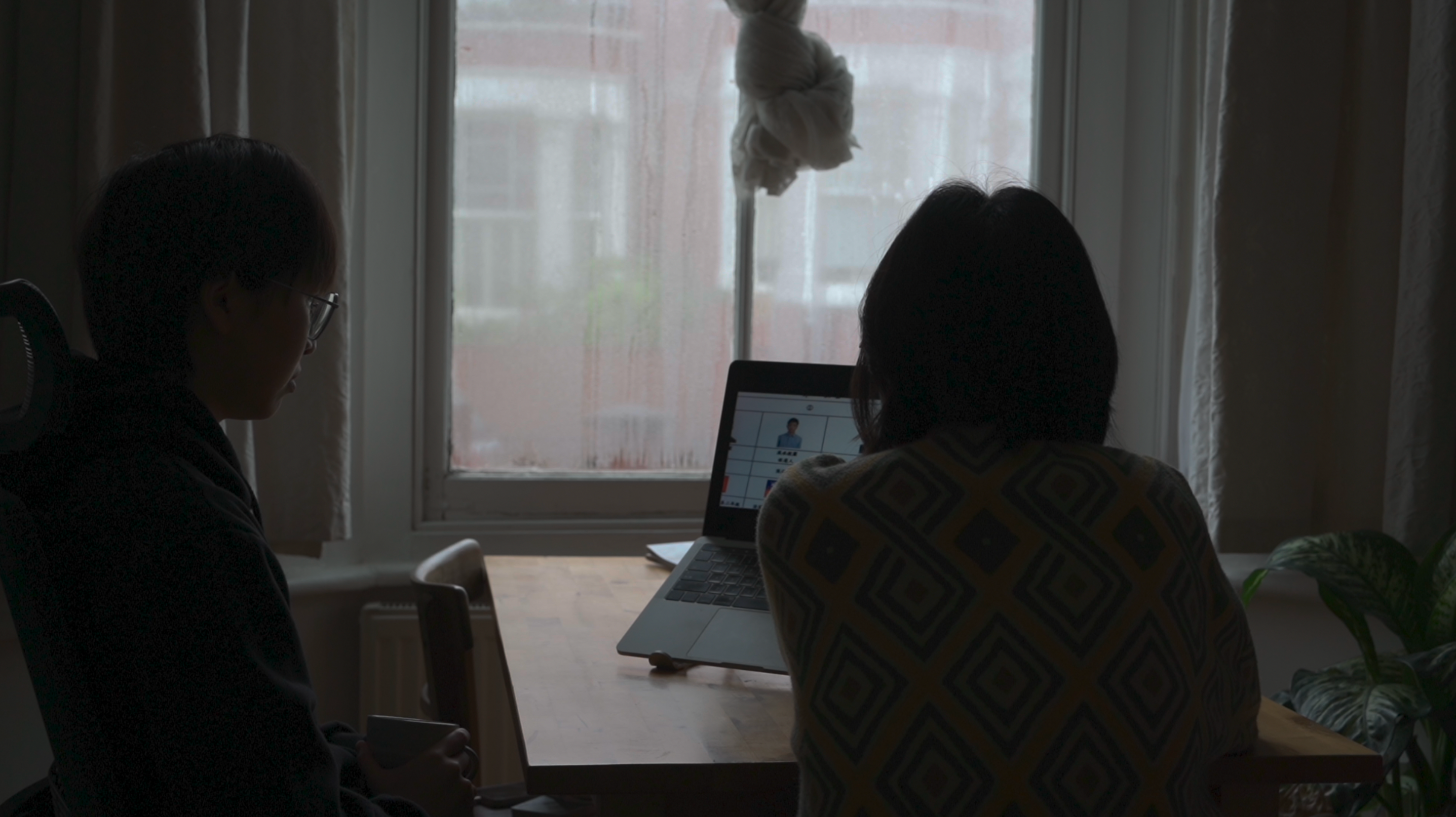Two figures look at a laptop.