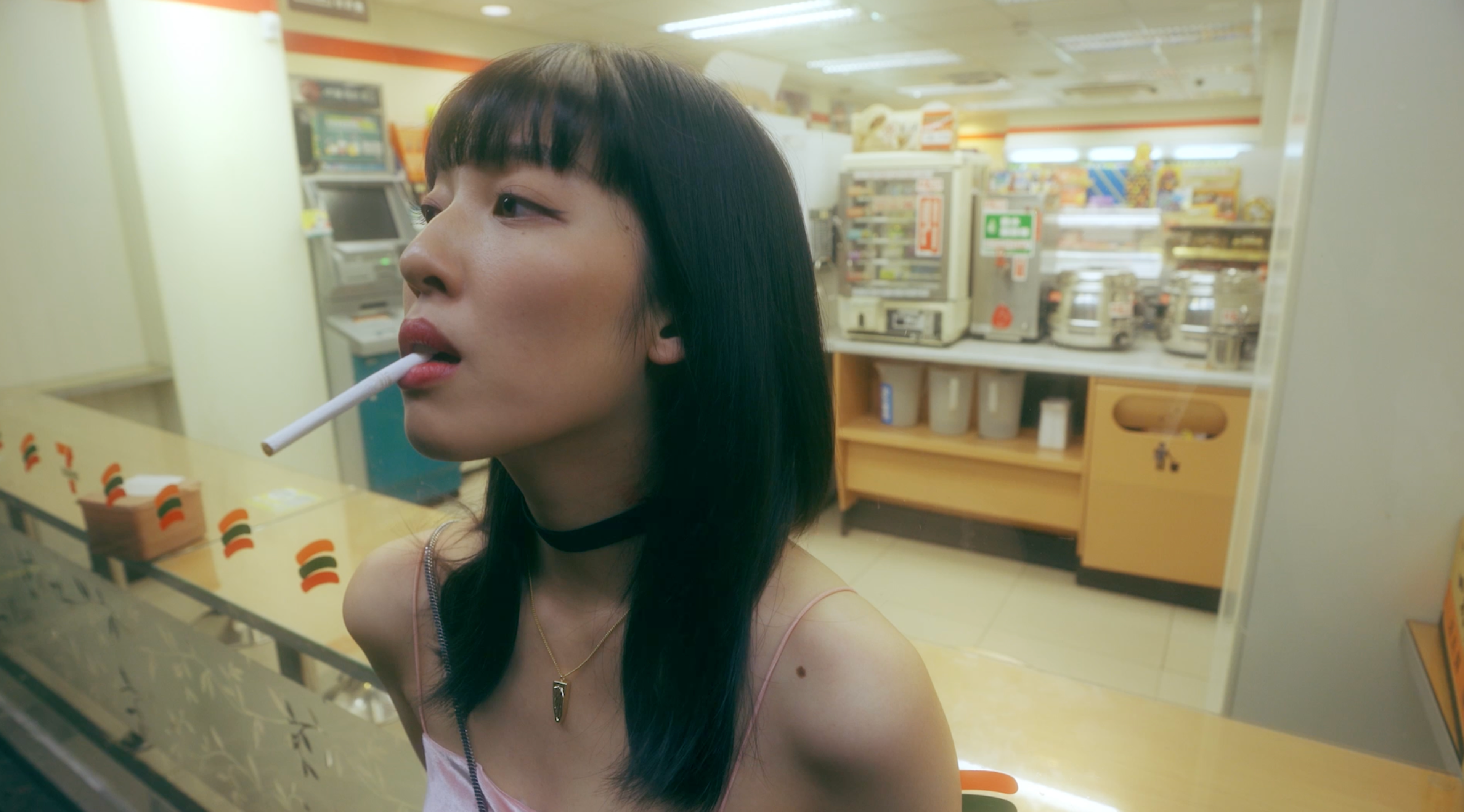 A girl with a cigarette in her mouth in front of a shop window.