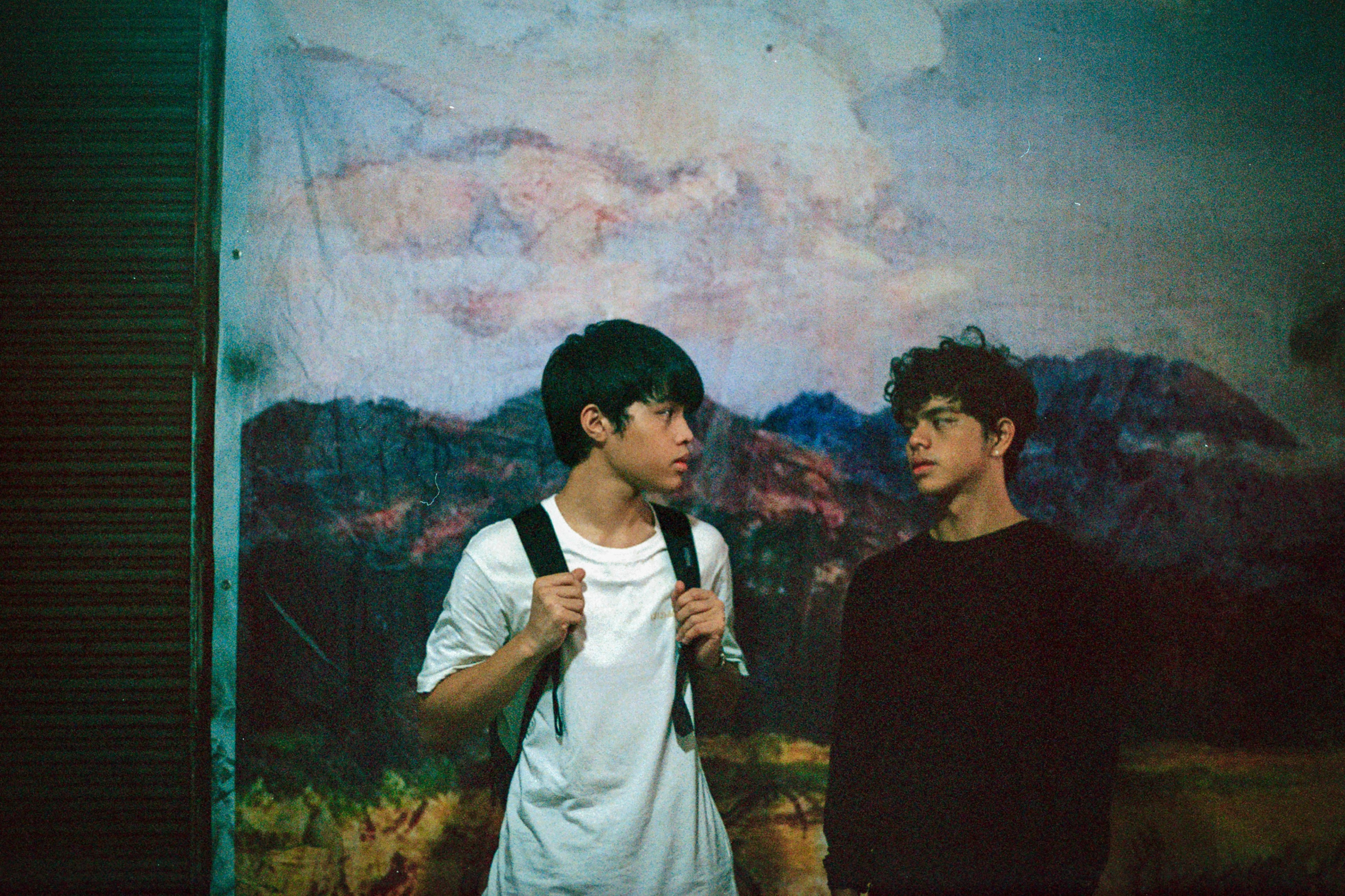Two teenage boys look at each other.