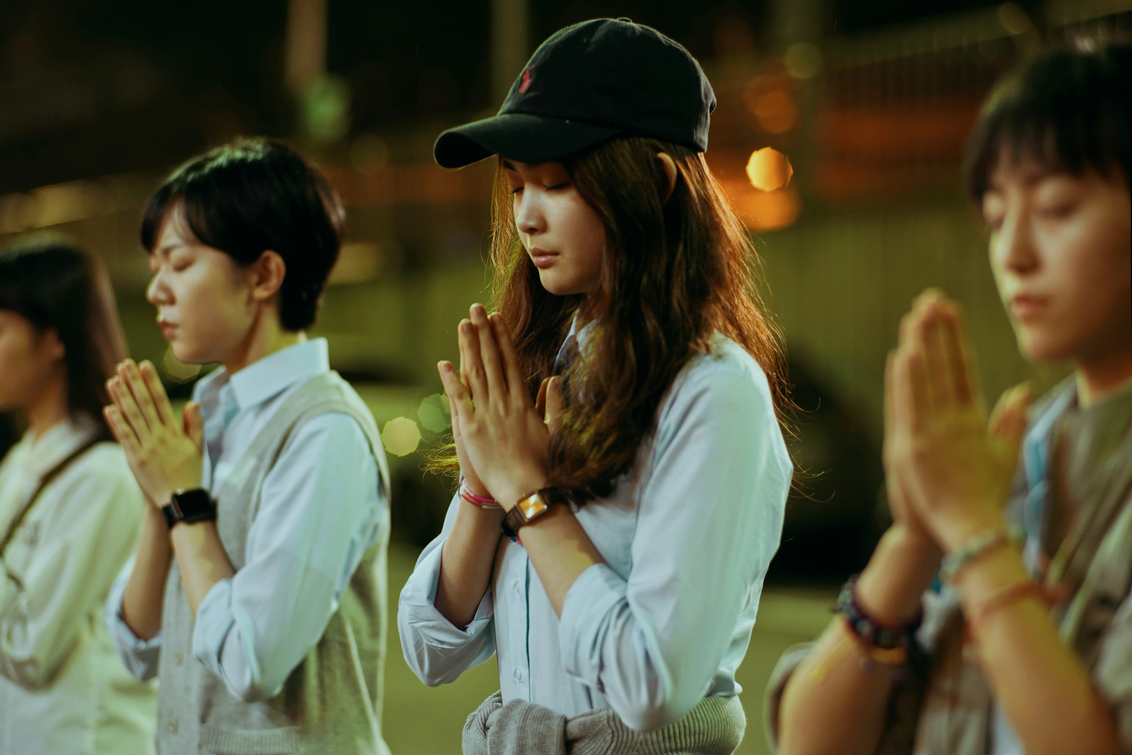 Four girls stand in a line praying.