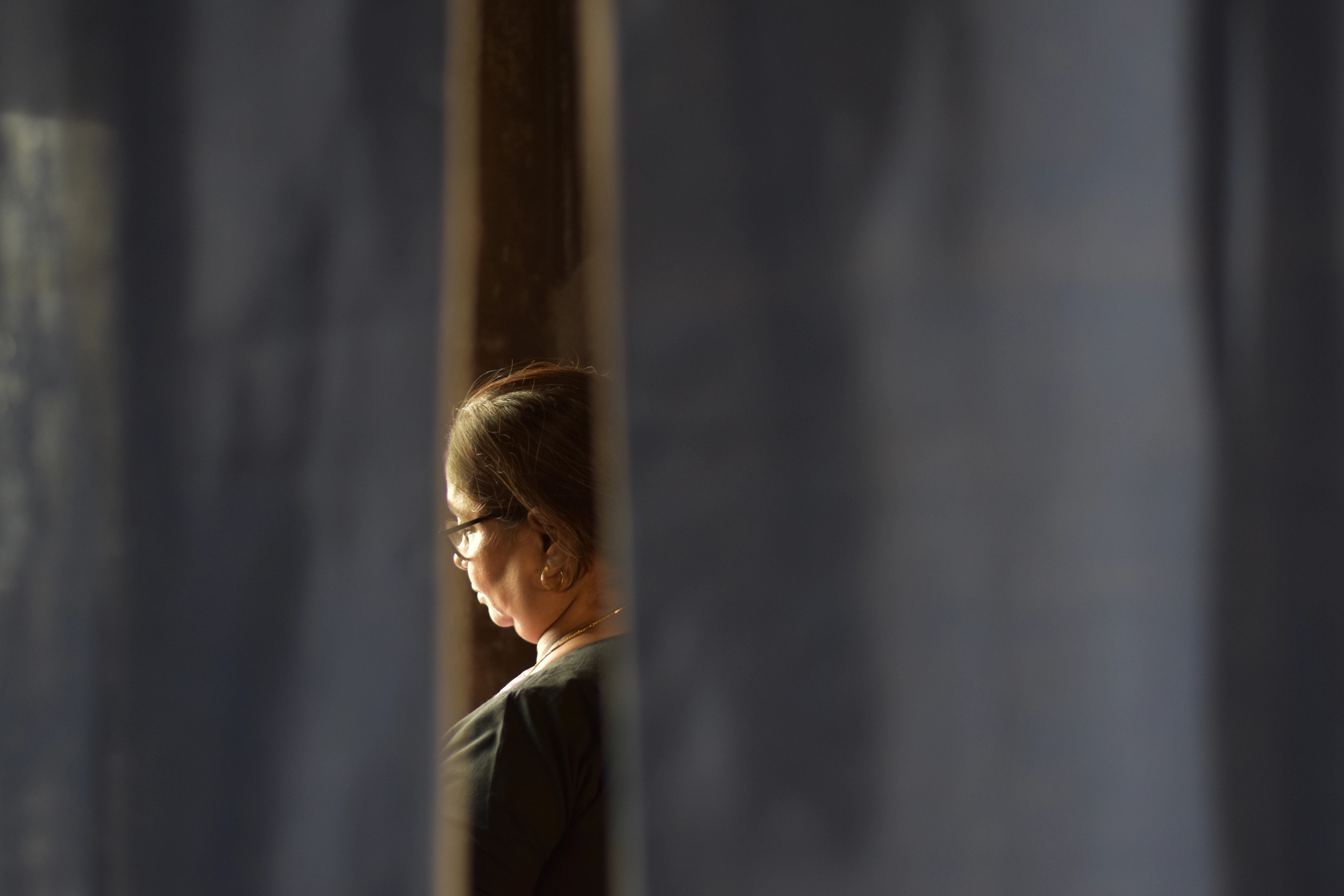 the back of a woman's head is framed by grey curtains.
