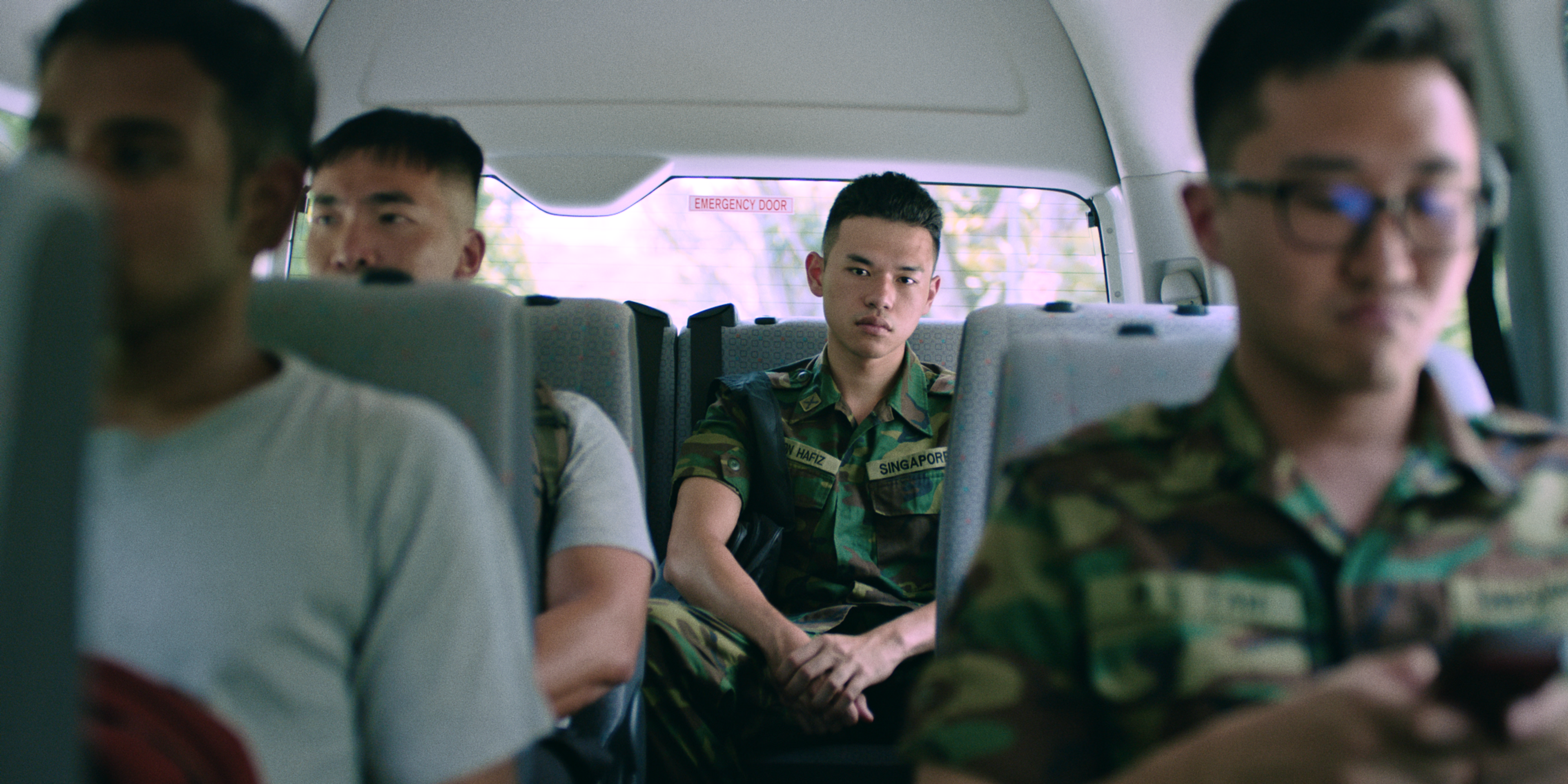 Men wearing army uniforms sit in a van.